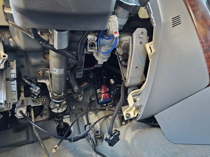 A car with the steering wheel removed and a bunch of wires coming out of it.