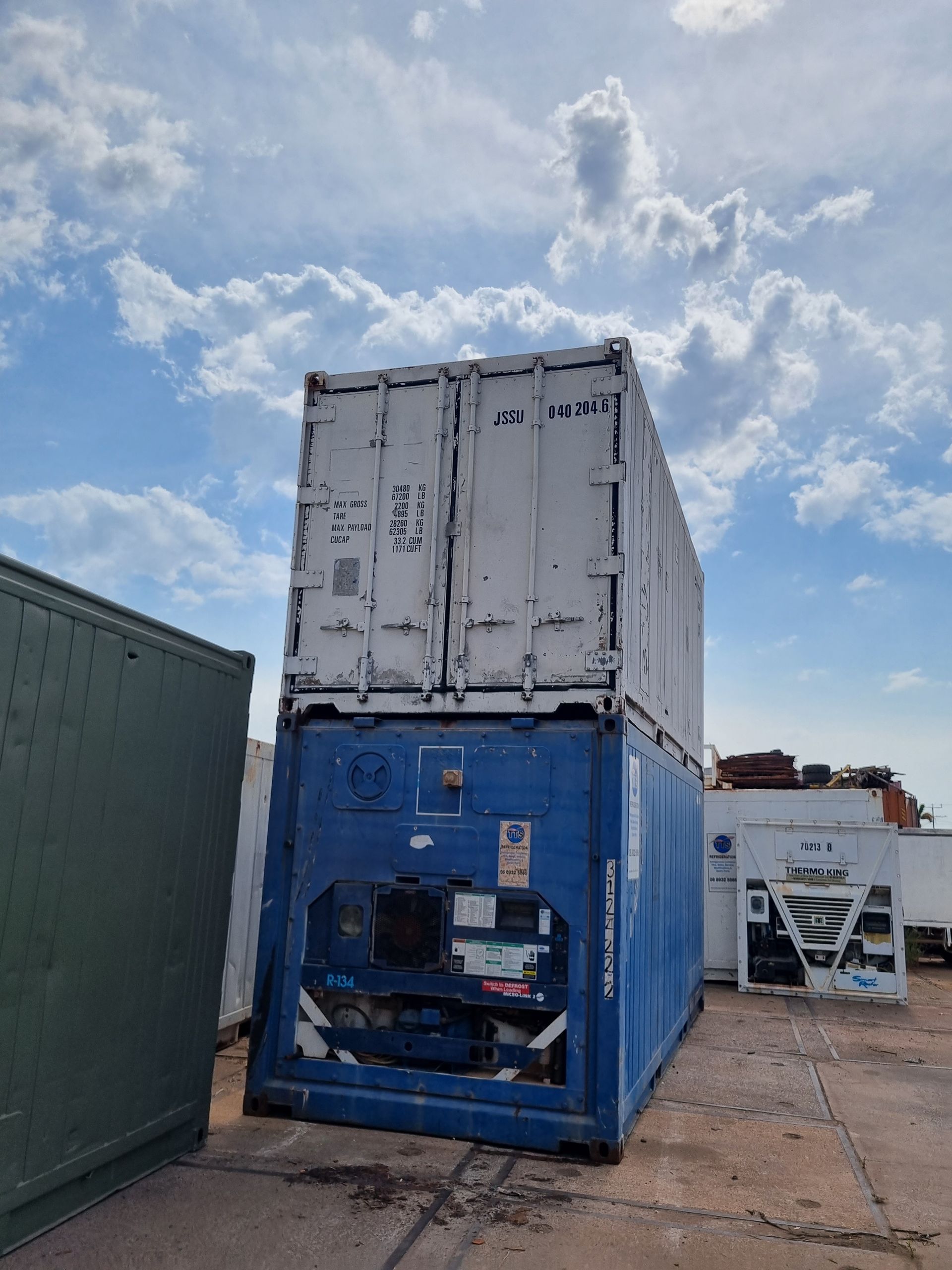 Two stacked shipping containers, one white, one blue, outdoors under a cloudy sky — TTS Refrigeration in Pinelands, NT