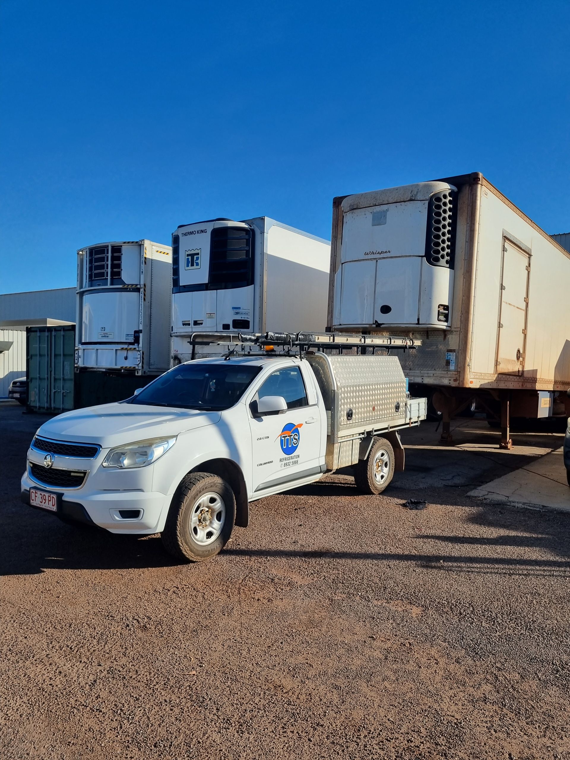 White pickup truck parked near refrigeration trailers on a gravel lot under a clear blue sky — TTS Refrigeration in Pinelands, NT