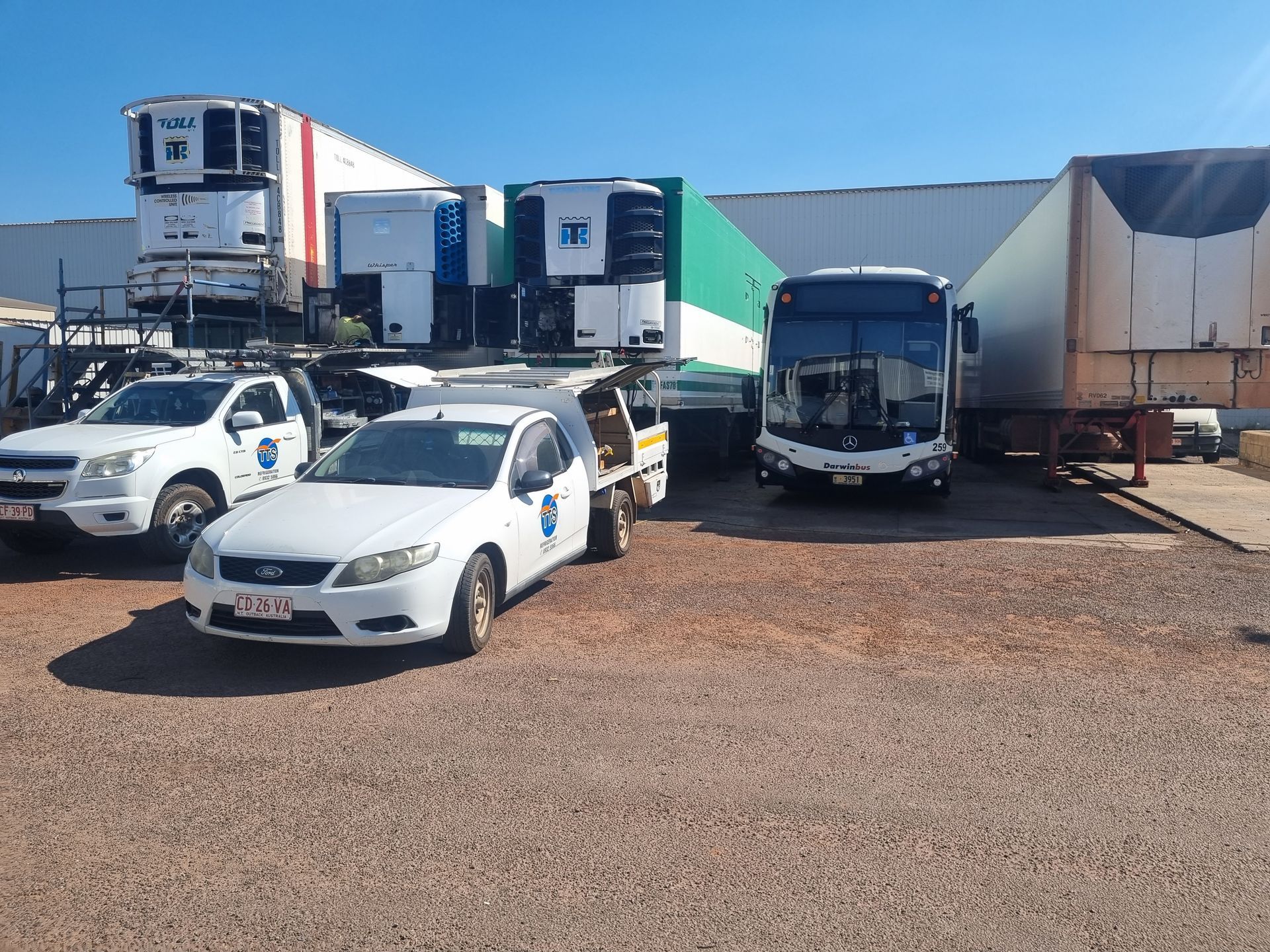 White vehicles parked outdoors. Includes trucks, a bus, and trailers — TTS Refrigeration in Pinelands, NT