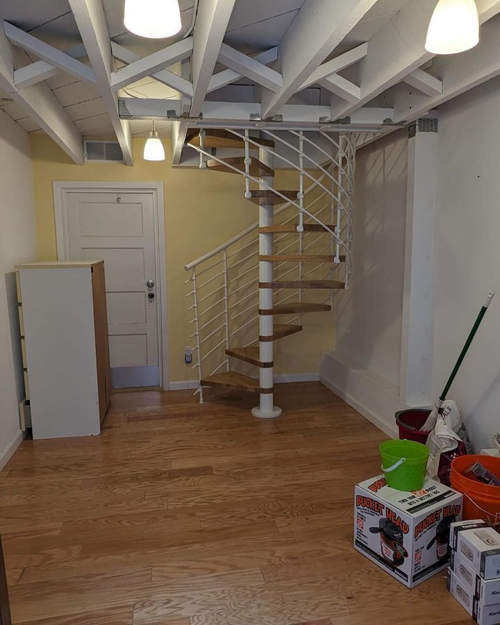 A room with a spiral staircase and boxes on the floor