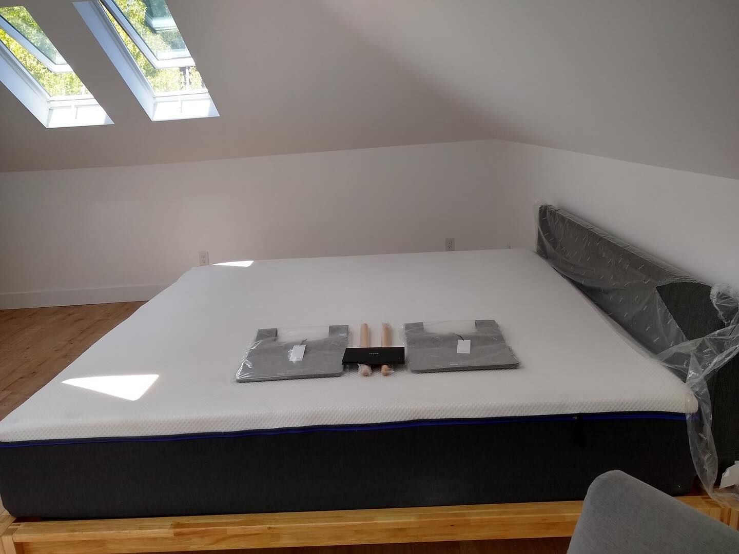 A mattress is sitting on top of a wooden bed frame in a room.