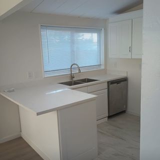 A kitchen with two sinks , a dishwasher , and a window.