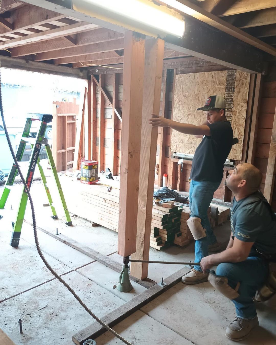 Two men are working on a wooden structure in a garage.