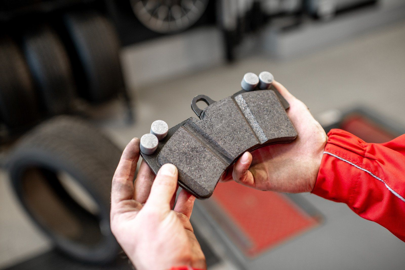 A person is holding a pair of brake pads in their hands.