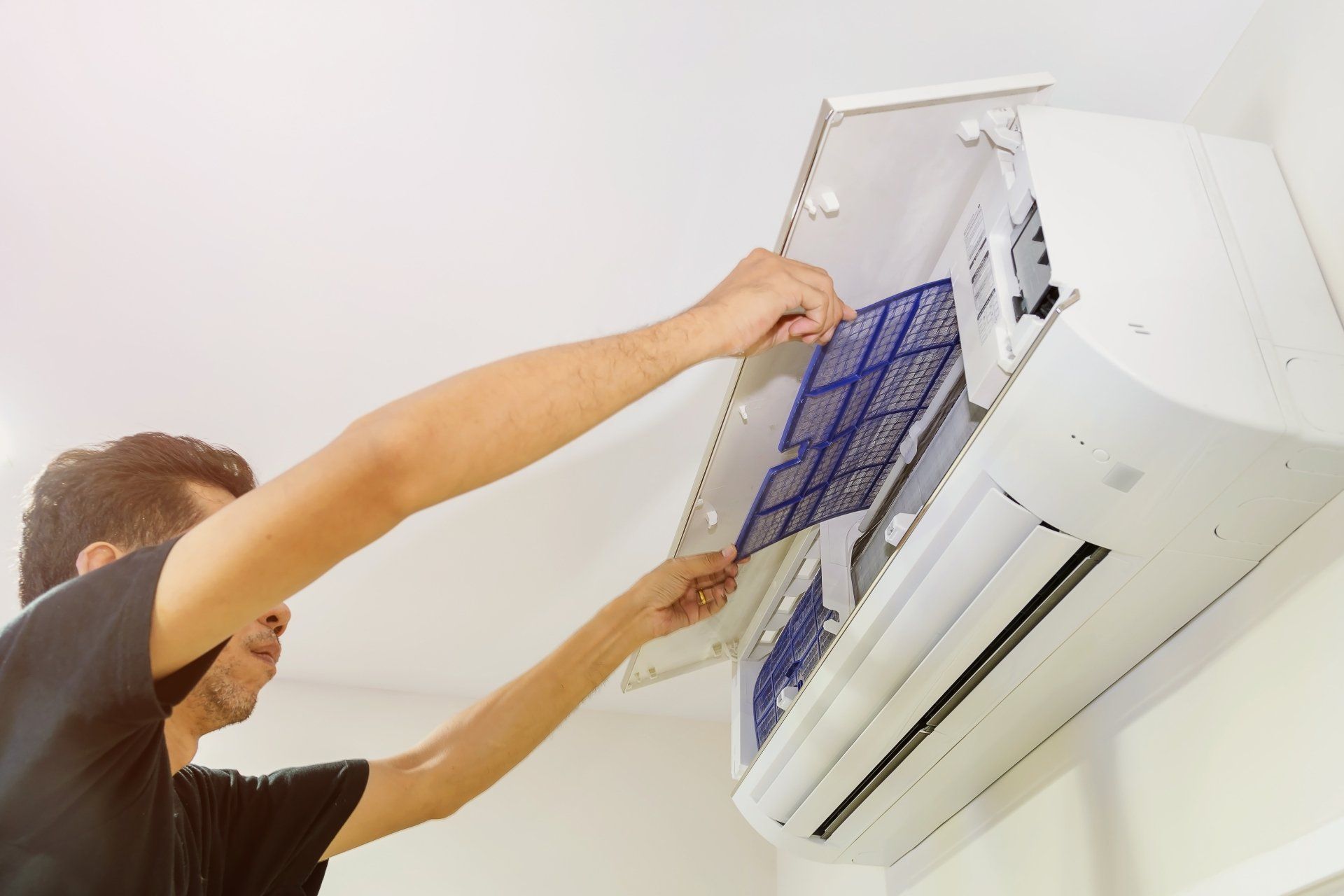 A man is cleaning an air conditioner with a filter.