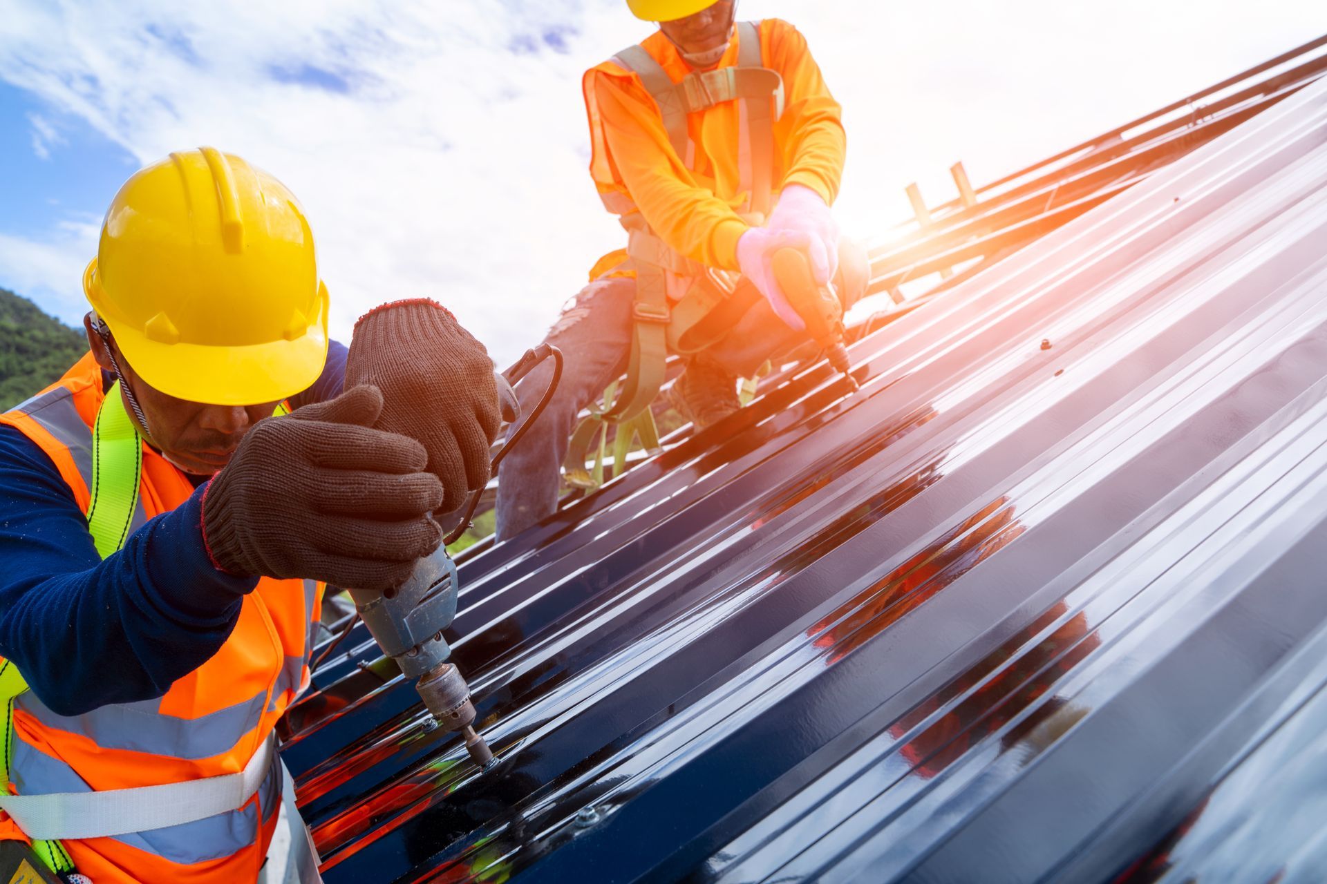 Two roofers in safety gear repairing a commercial metal roof. Two roofers in safety gear repairing a commercial metal roof.