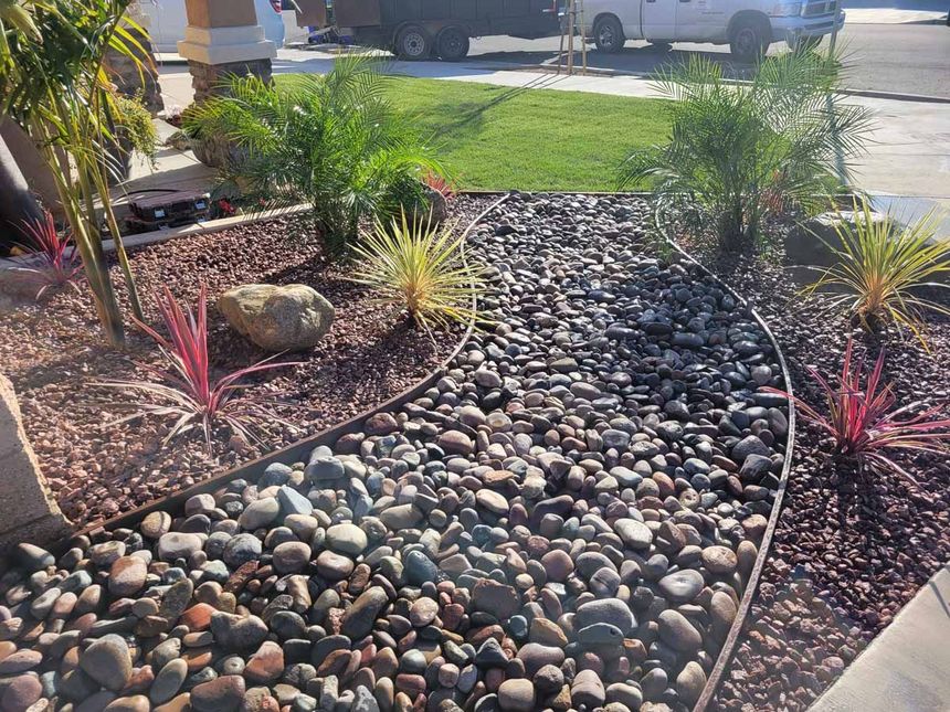 A garden with rocks , plants and a truck parked in the background