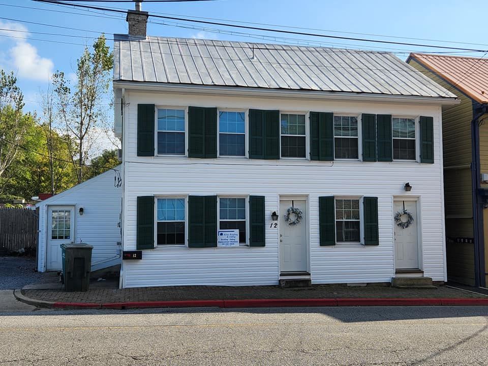 A white house with green shutters is for sale