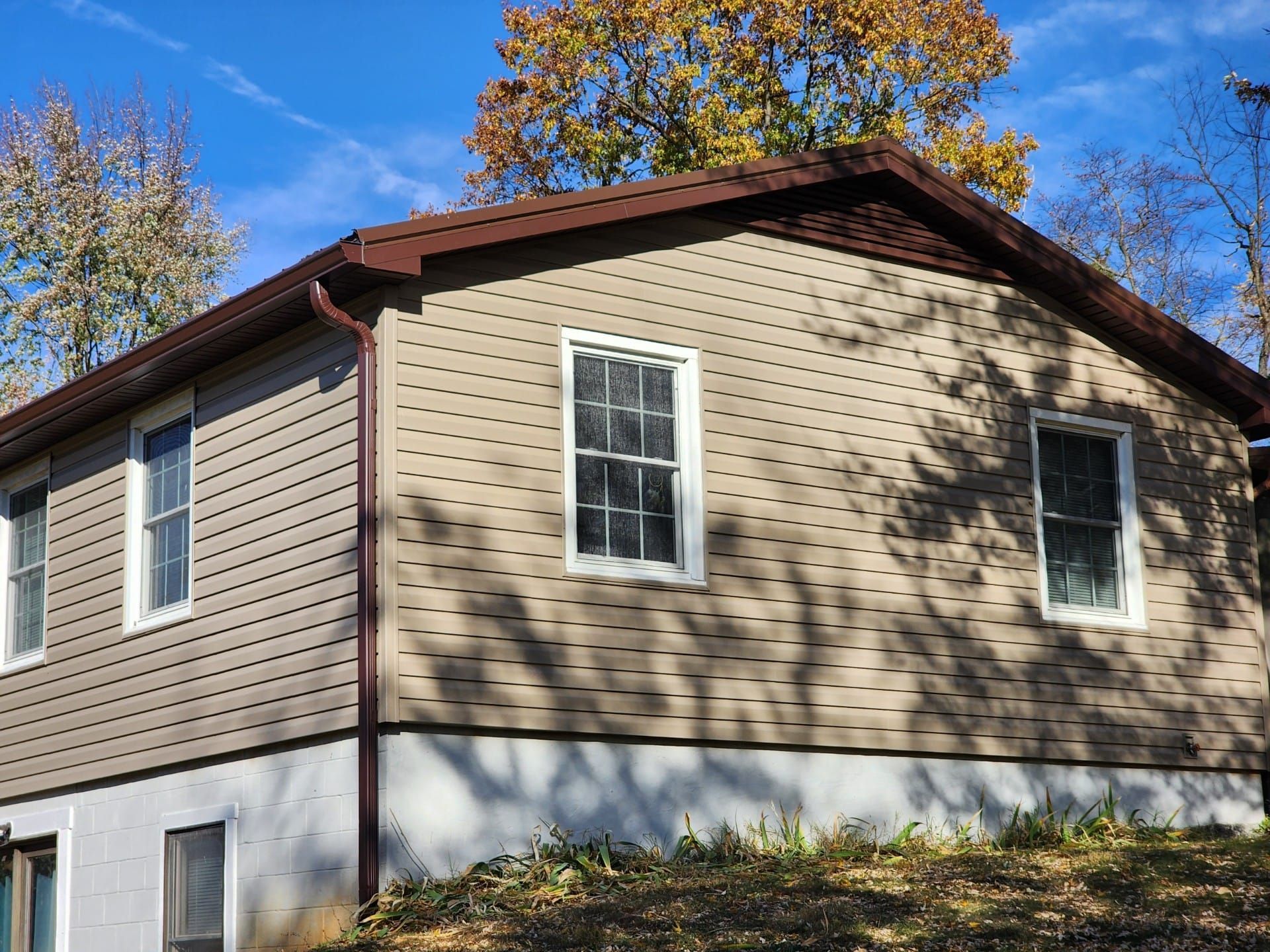 A house with a brown roof and siding is sitting on top of a hill.