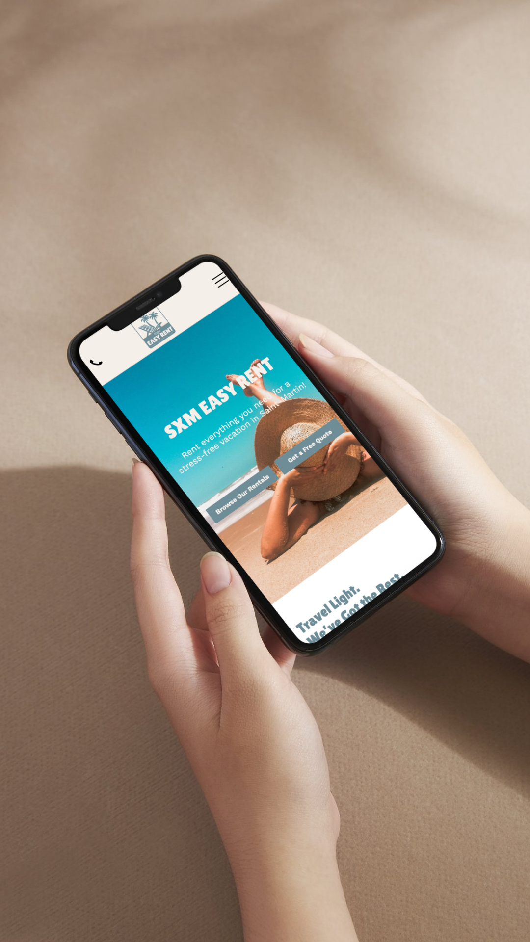 Hands holding a phone, displaying a beach resort website on a beige surface.