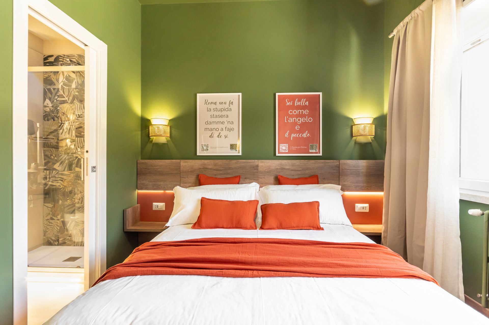 Una camera da letto con pareti verdi e un letto con cuscini arancioni