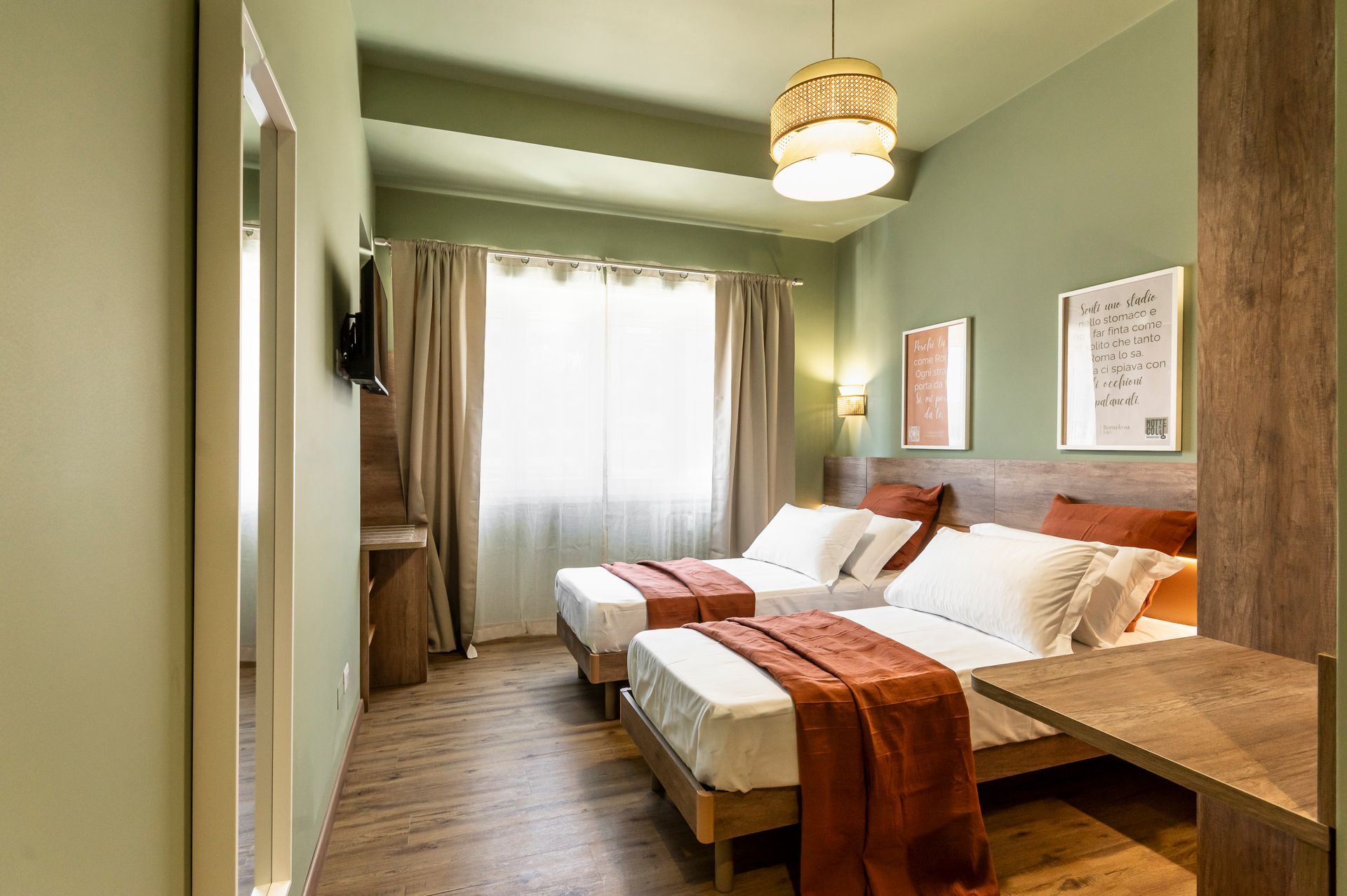 Una camera d'albergo con due letti e una grande finestra