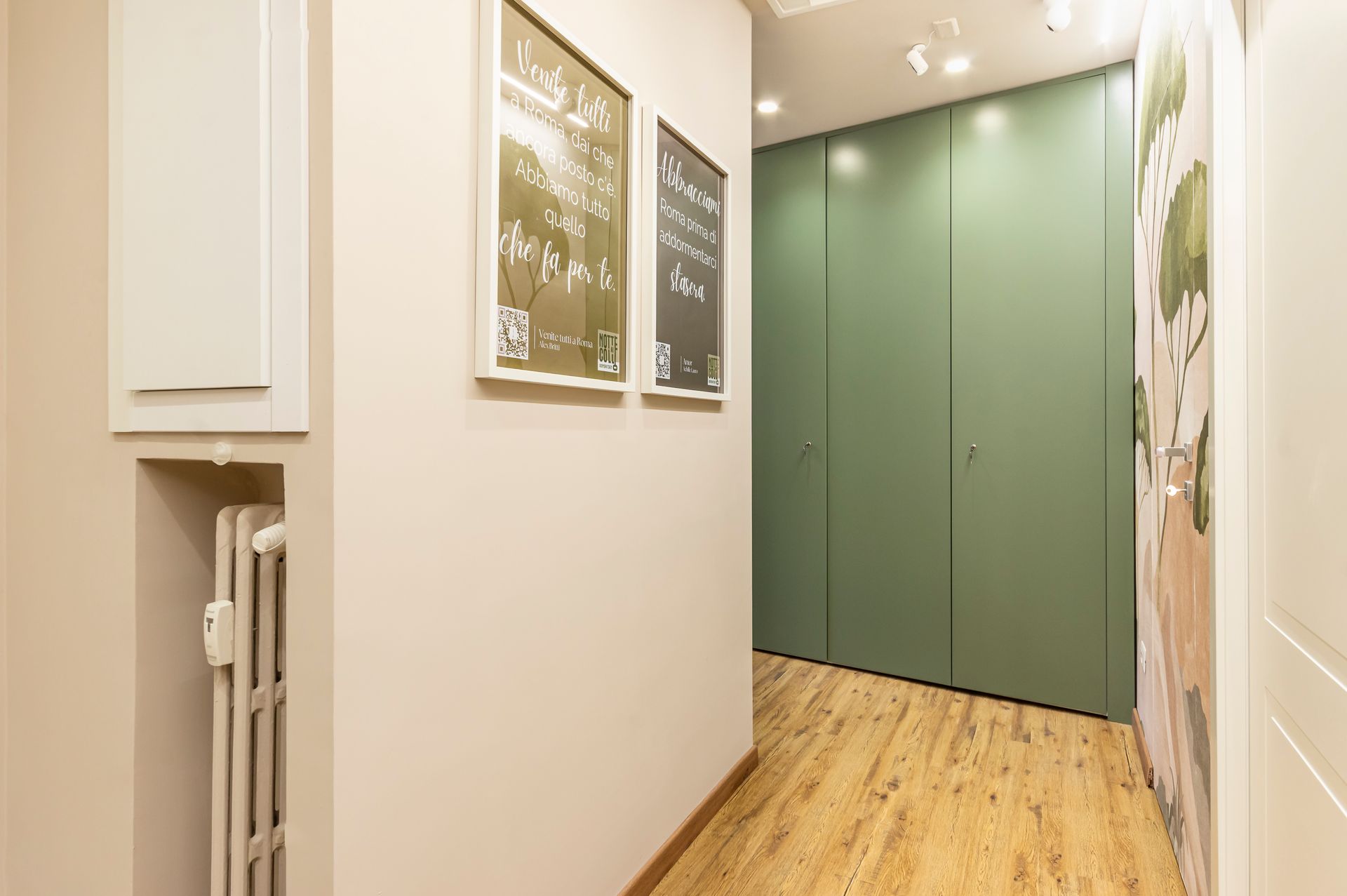 Un corridoio con un termosifone e qualche quadro sul muro