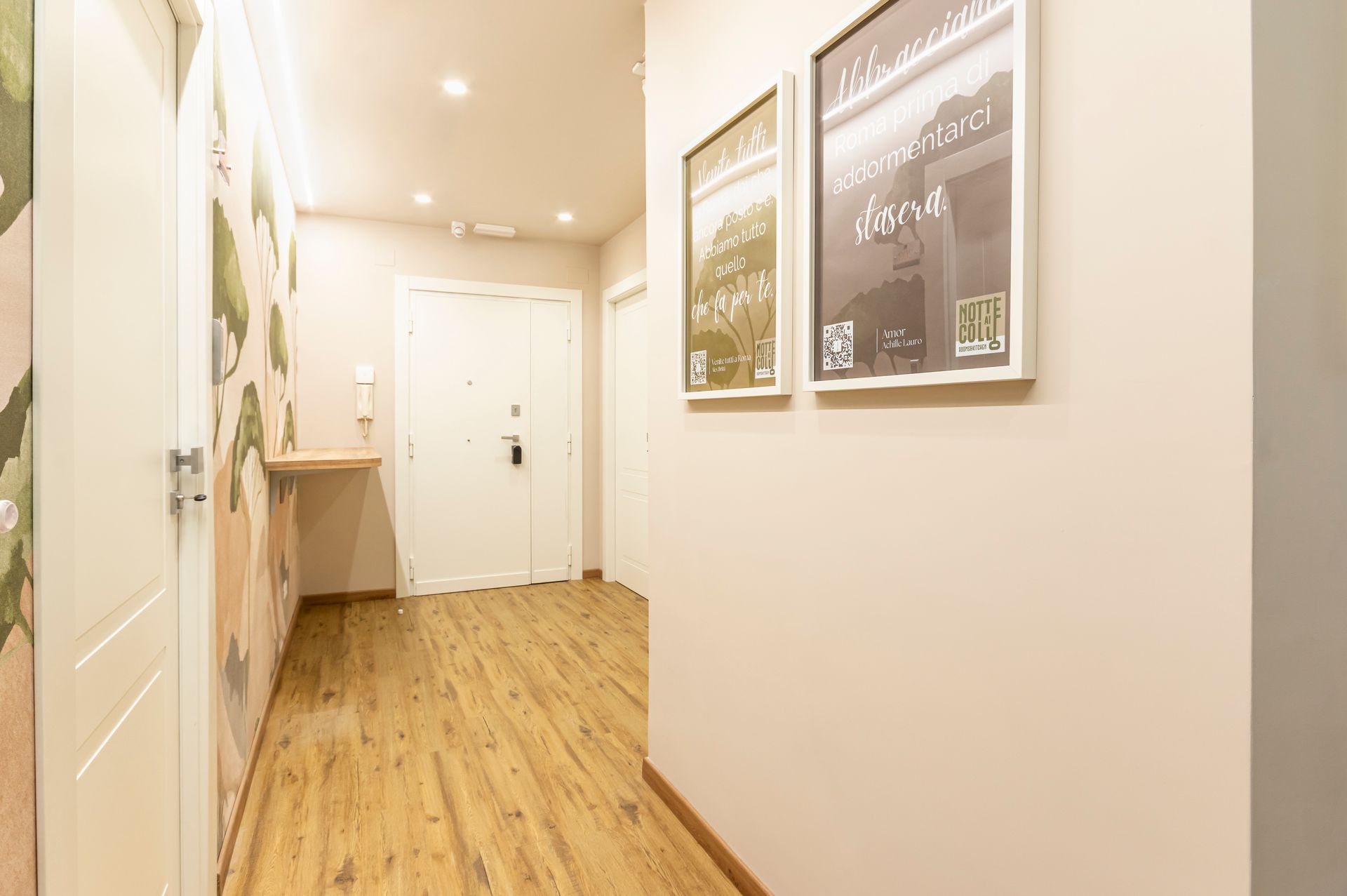 Un corridoio con pavimento in legno e due quadri incorniciati sul muro