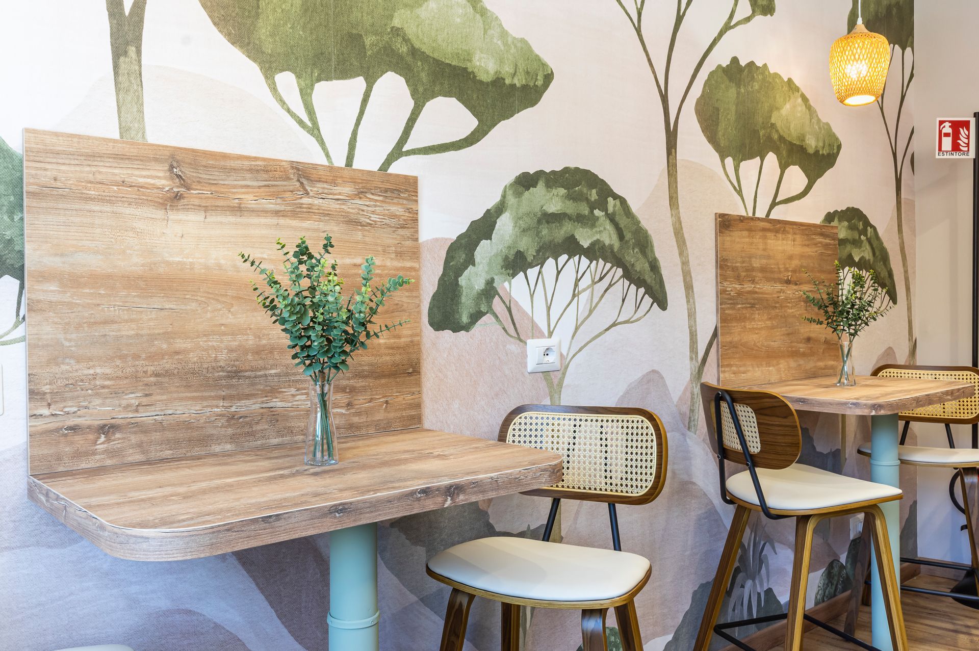 Tavoli e sedie davanti a un muro con alberi dipinti sopra