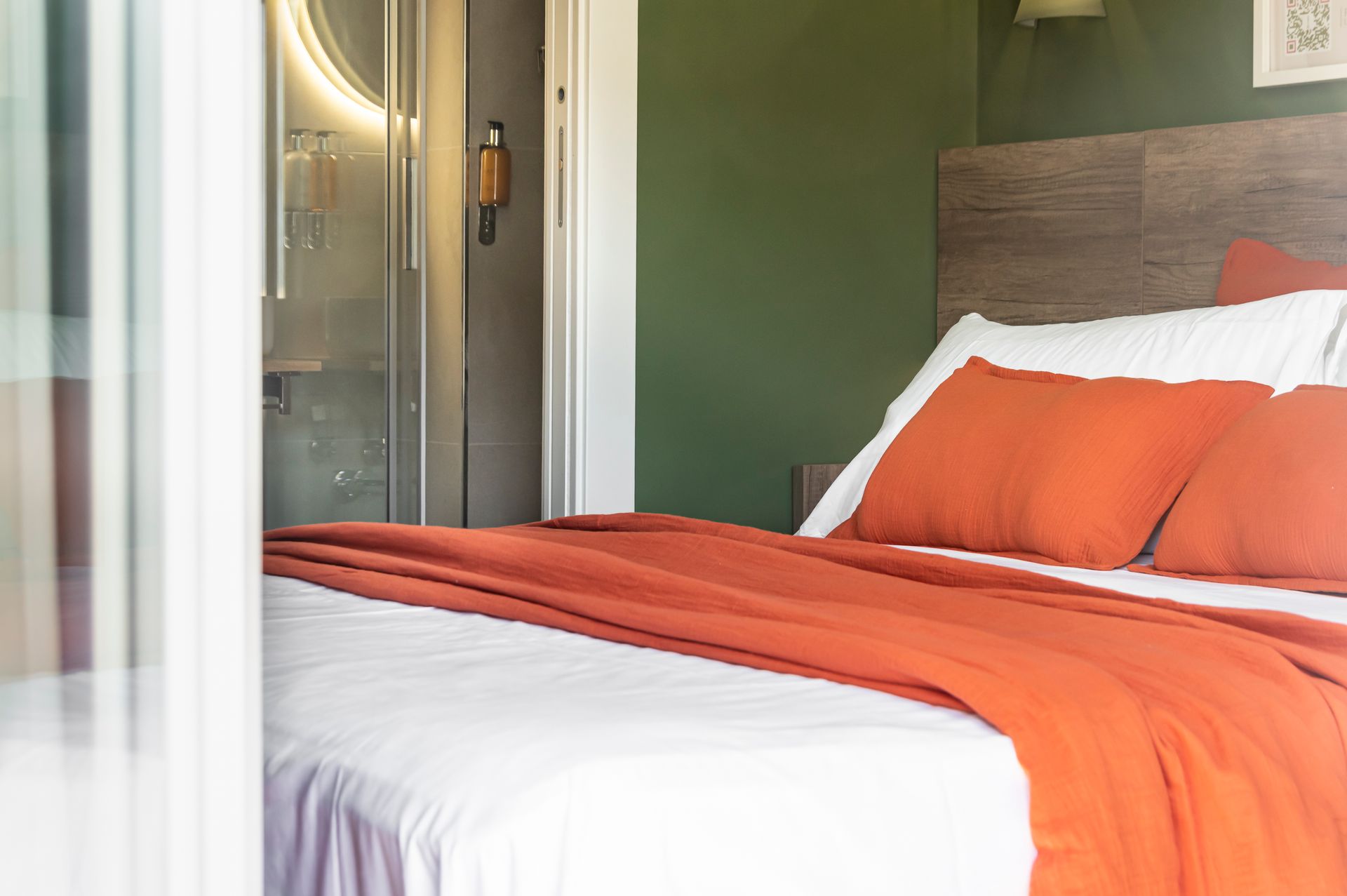 Un letto con lenzuola bianche e cuscini arancioni in una camera da letto