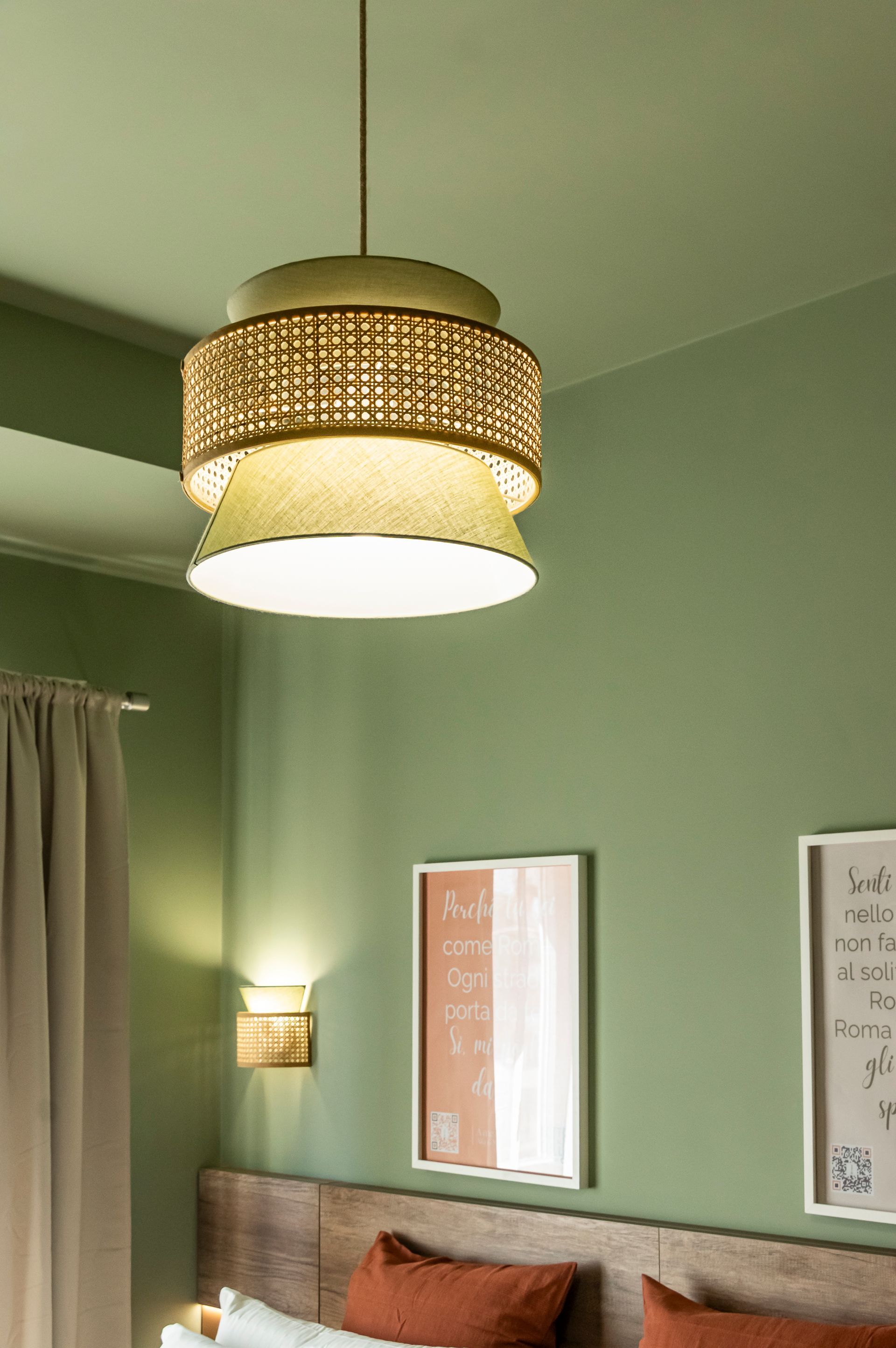 Una camera da letto con pareti verdi e una lampada appesa al soffitto