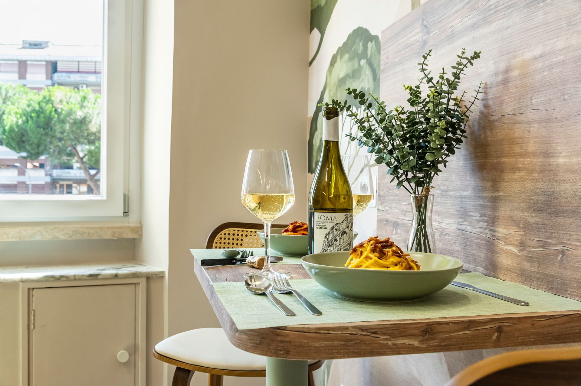 Una bottiglia di vino è appoggiata su un tavolo accanto a una ciotola di cibo