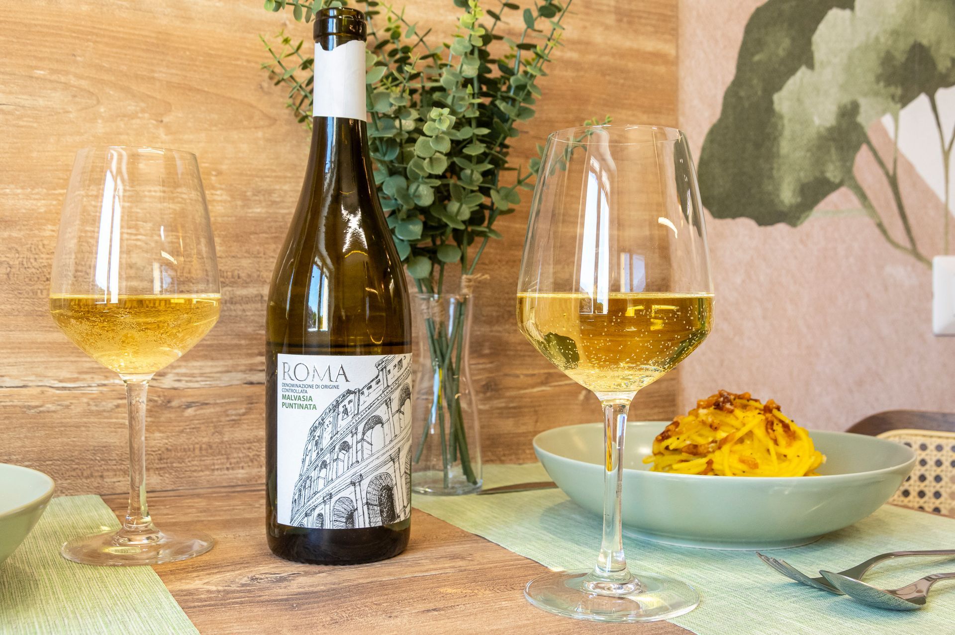 Una bottiglia di vino è appoggiata su un tavolo accanto a due bicchieri di vino