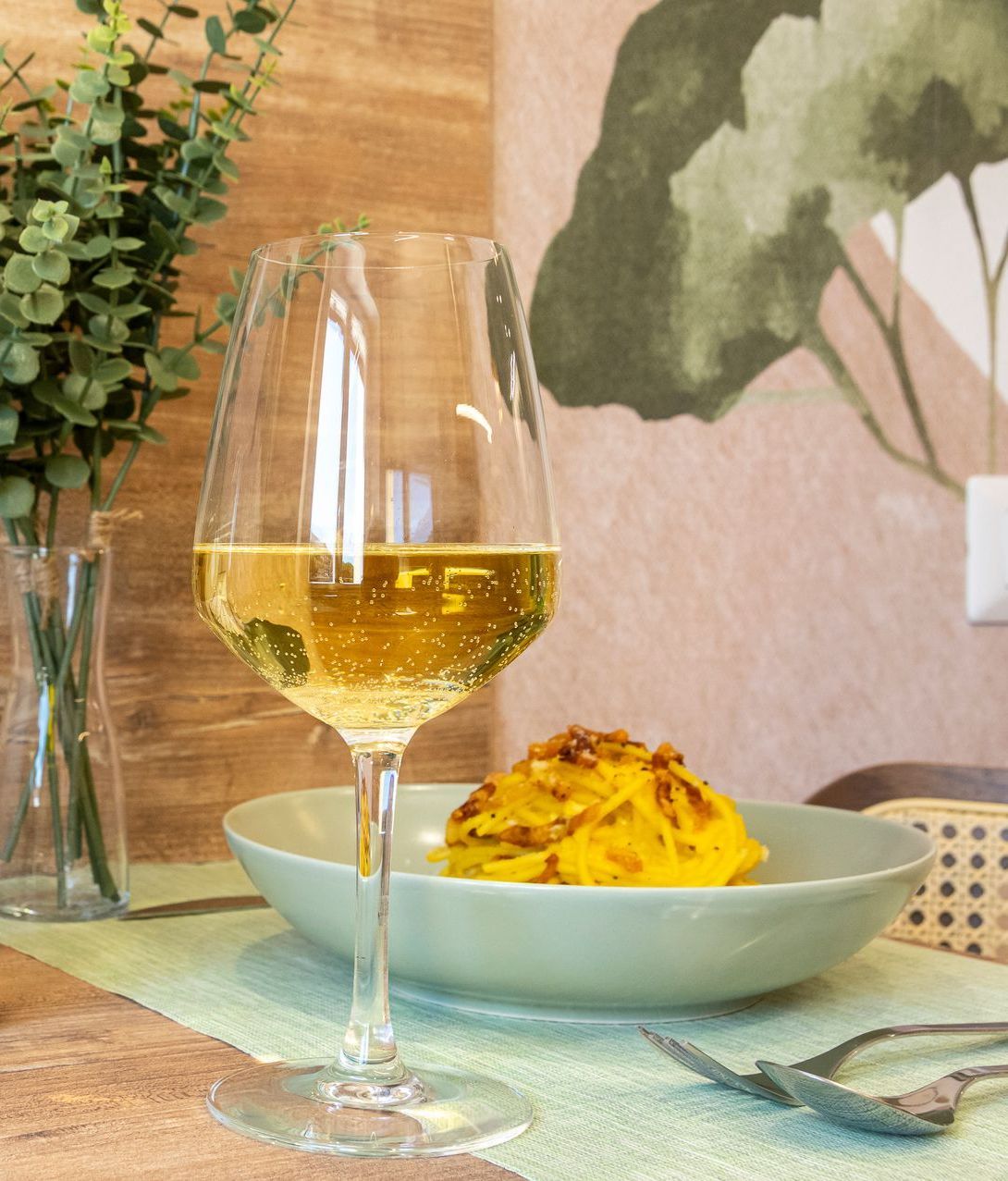 Un bicchiere di vino è appoggiato su un tavolo accanto a un piatto di cibo