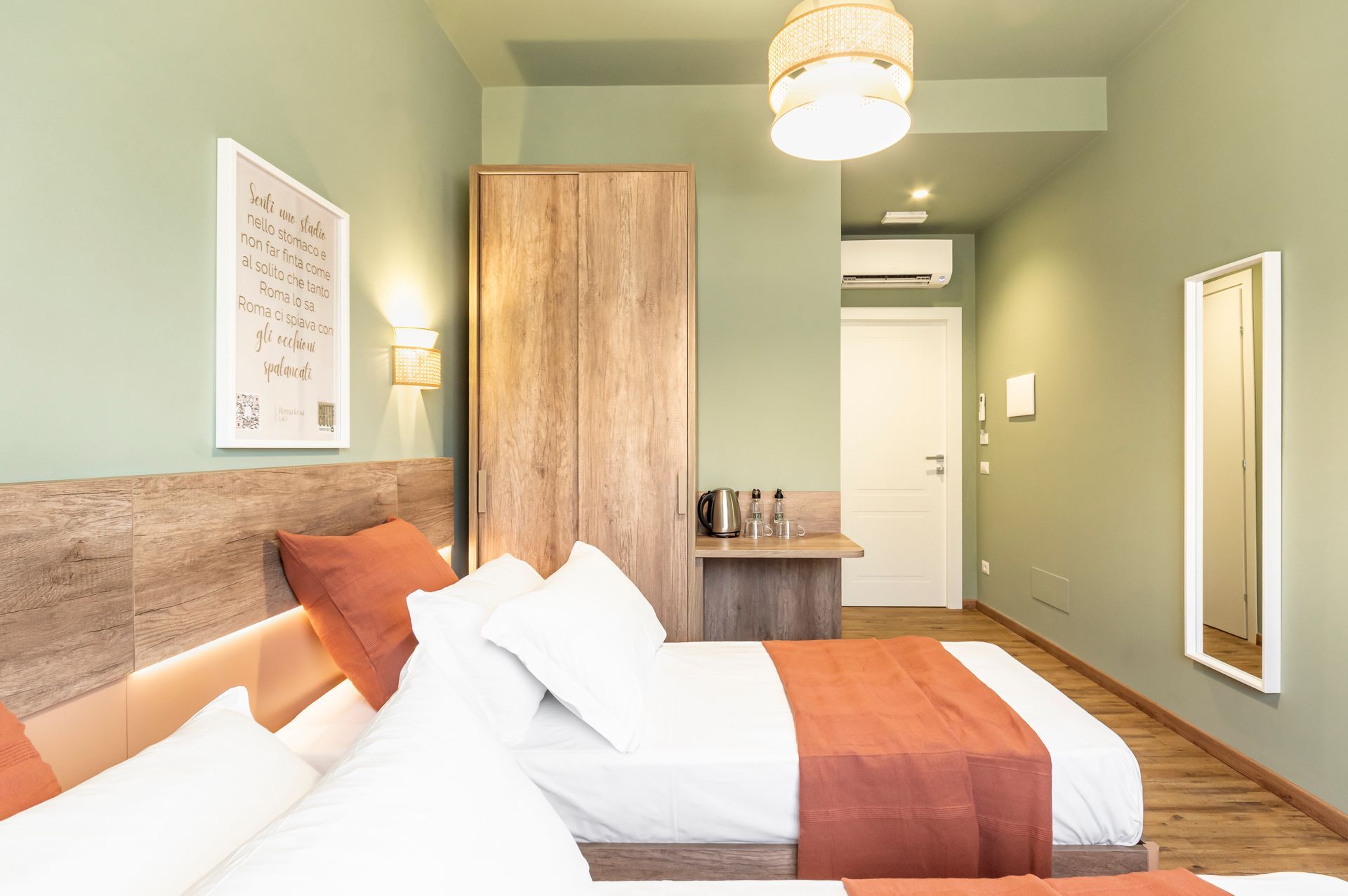 Una camera d'albergo con due letti e uno specchio