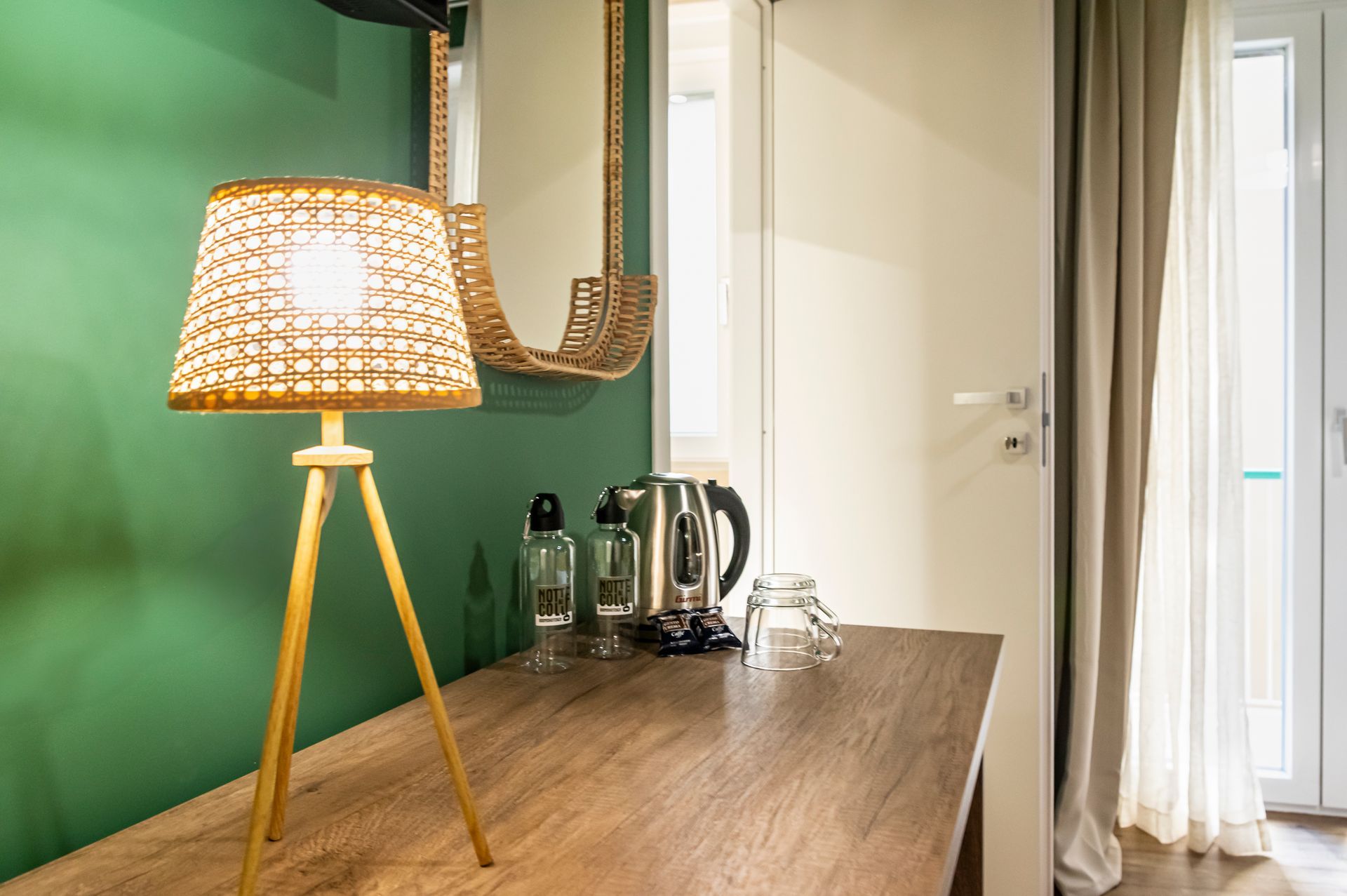 Una lampada è appoggiata su un tavolo di legno davanti a una parete verde