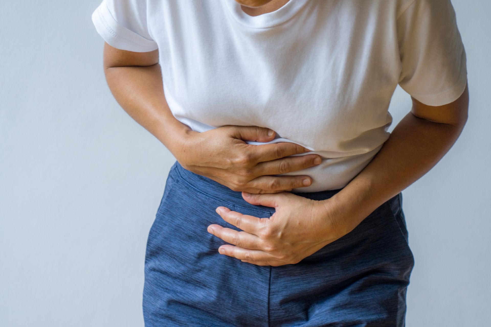 Woman clutching lower abdomen, seeking bladder pain treatment for discomfort and cramping.