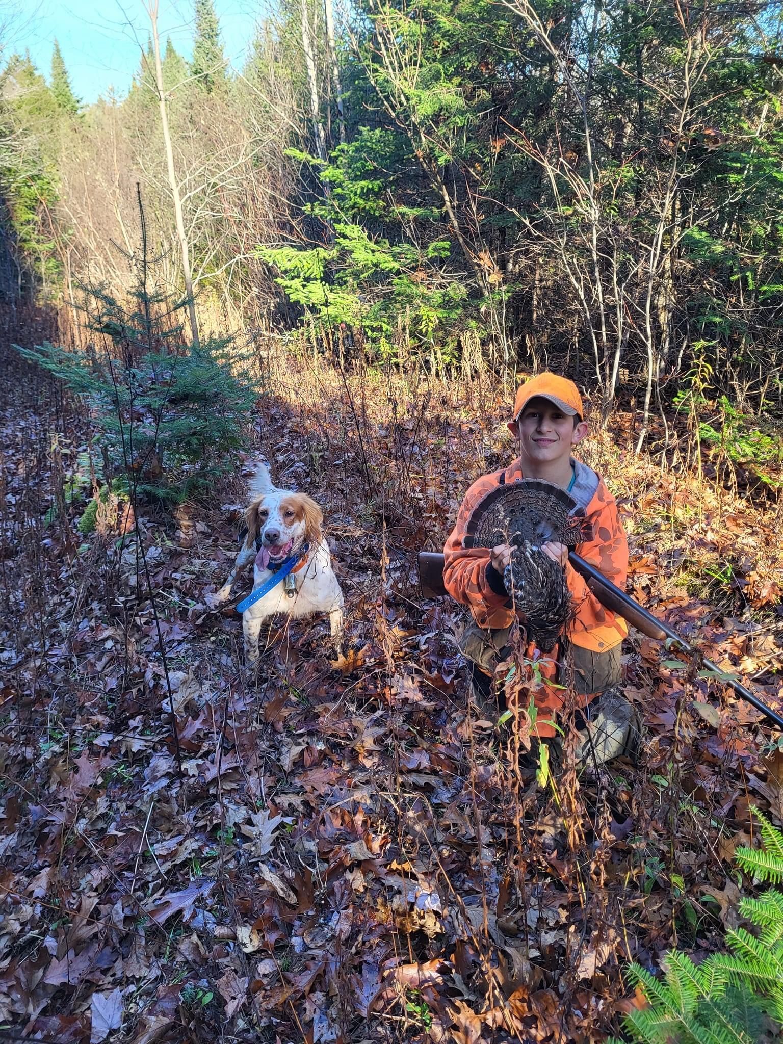A man and a dog are standing next to each other in the woods.