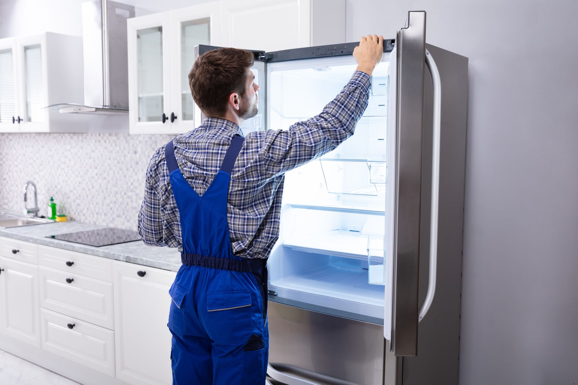 A man is inspecting a refrigerator.