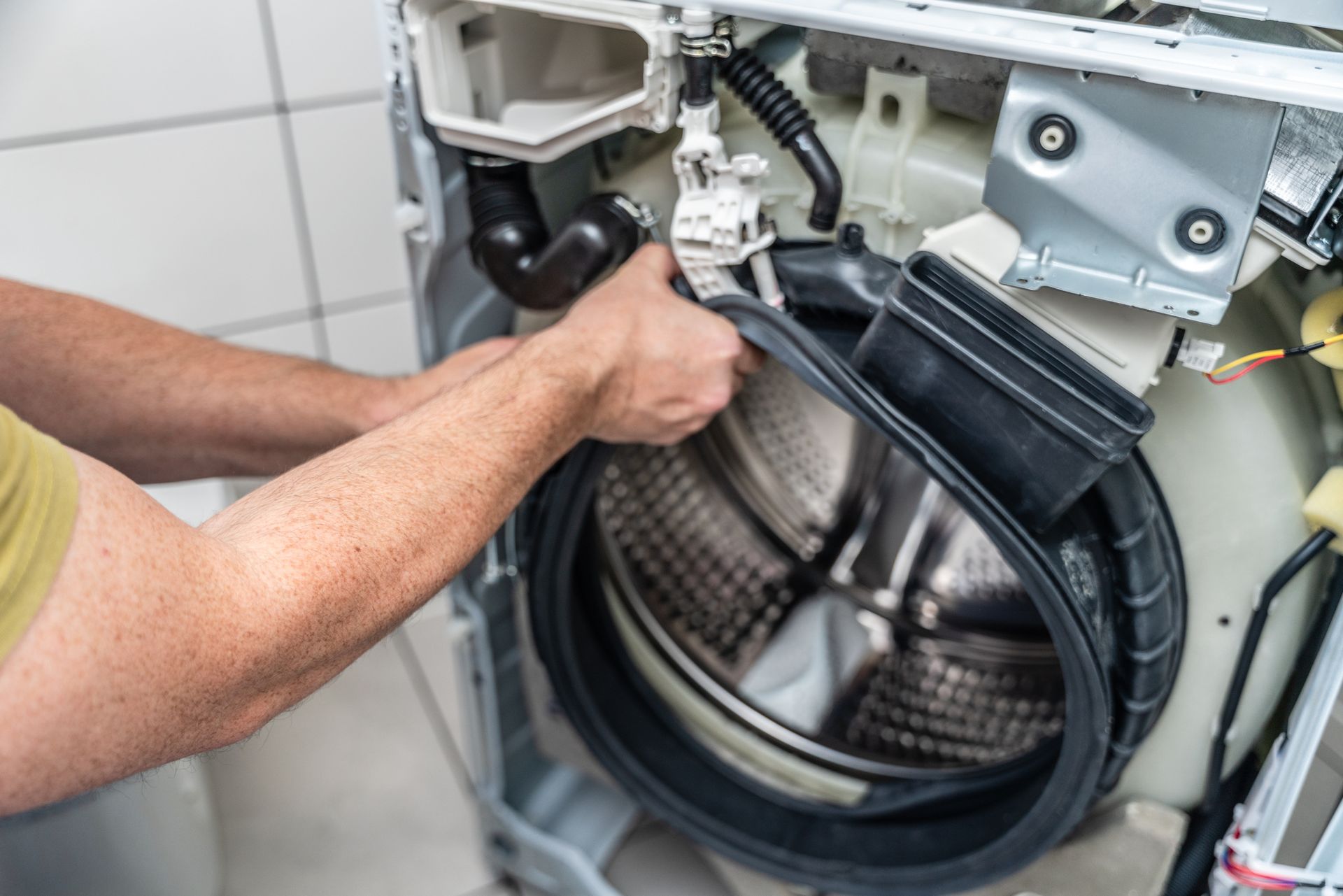Close View of the hands of a repairman fixing a stripped washing machine.
