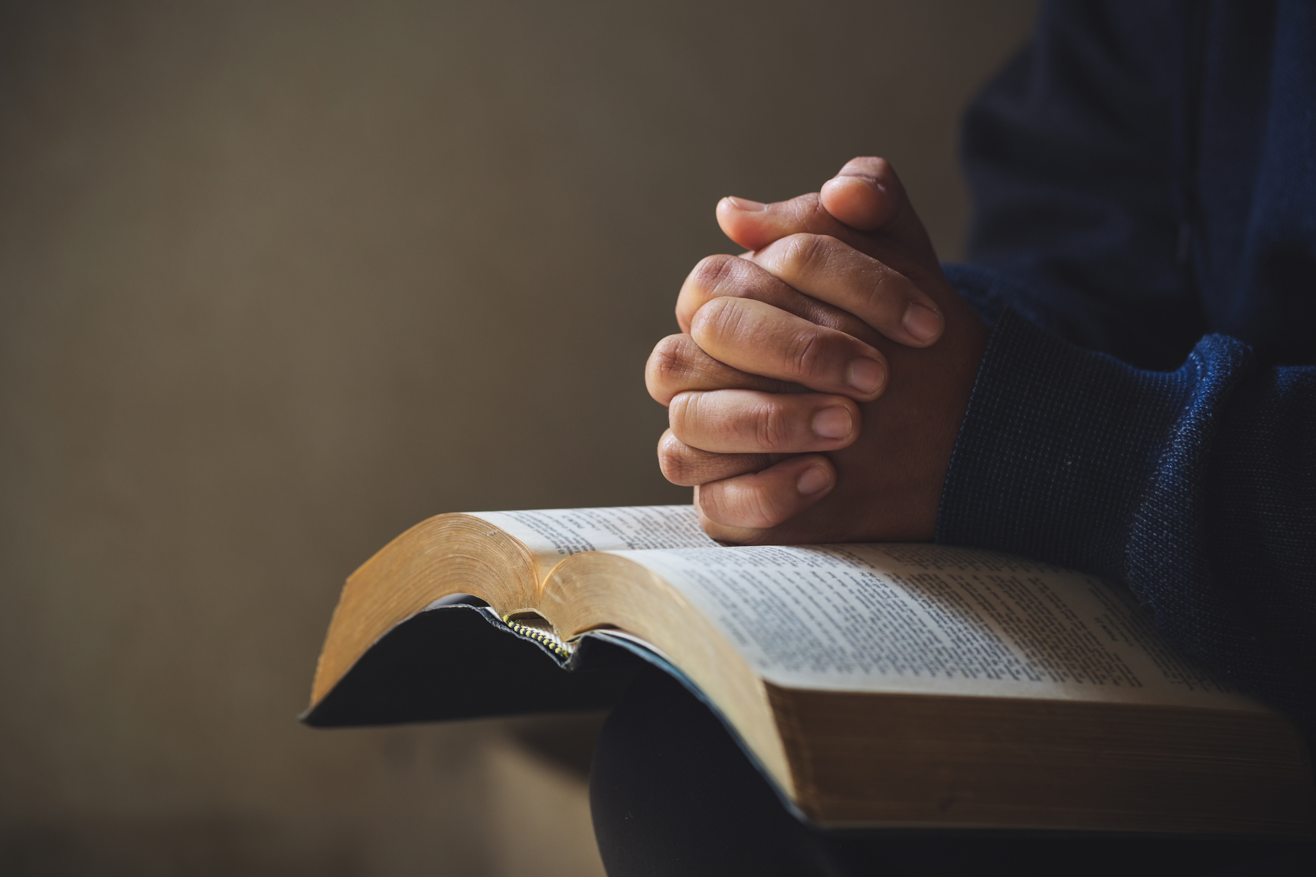 Hands clasped in prayer over an open book.