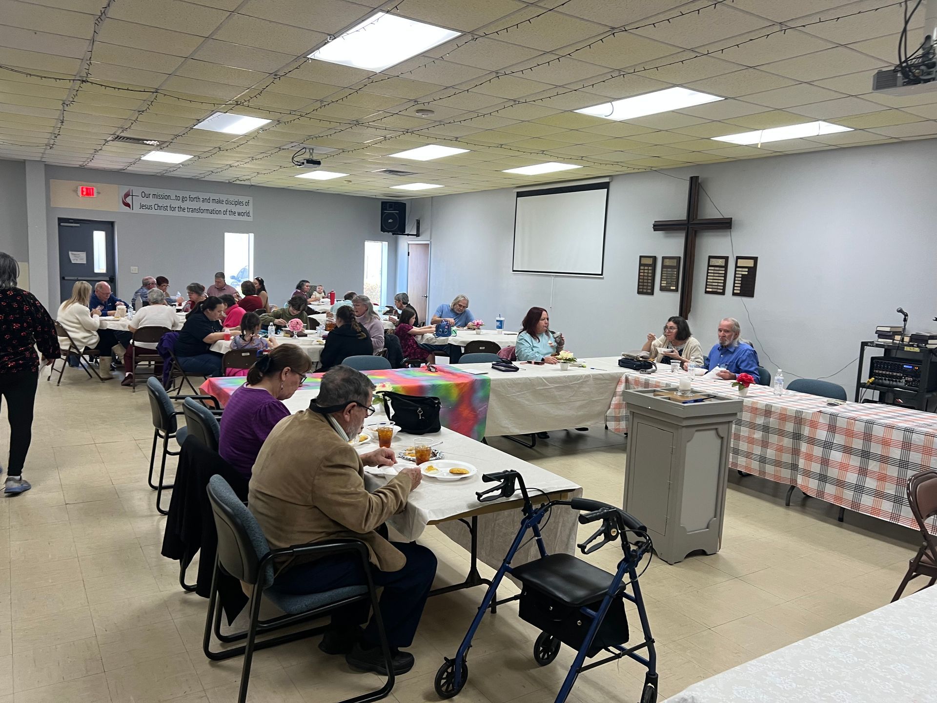 A salad with grilled chicken at a table with two people. One wears a yellow shirt, the other, a pink shirt.