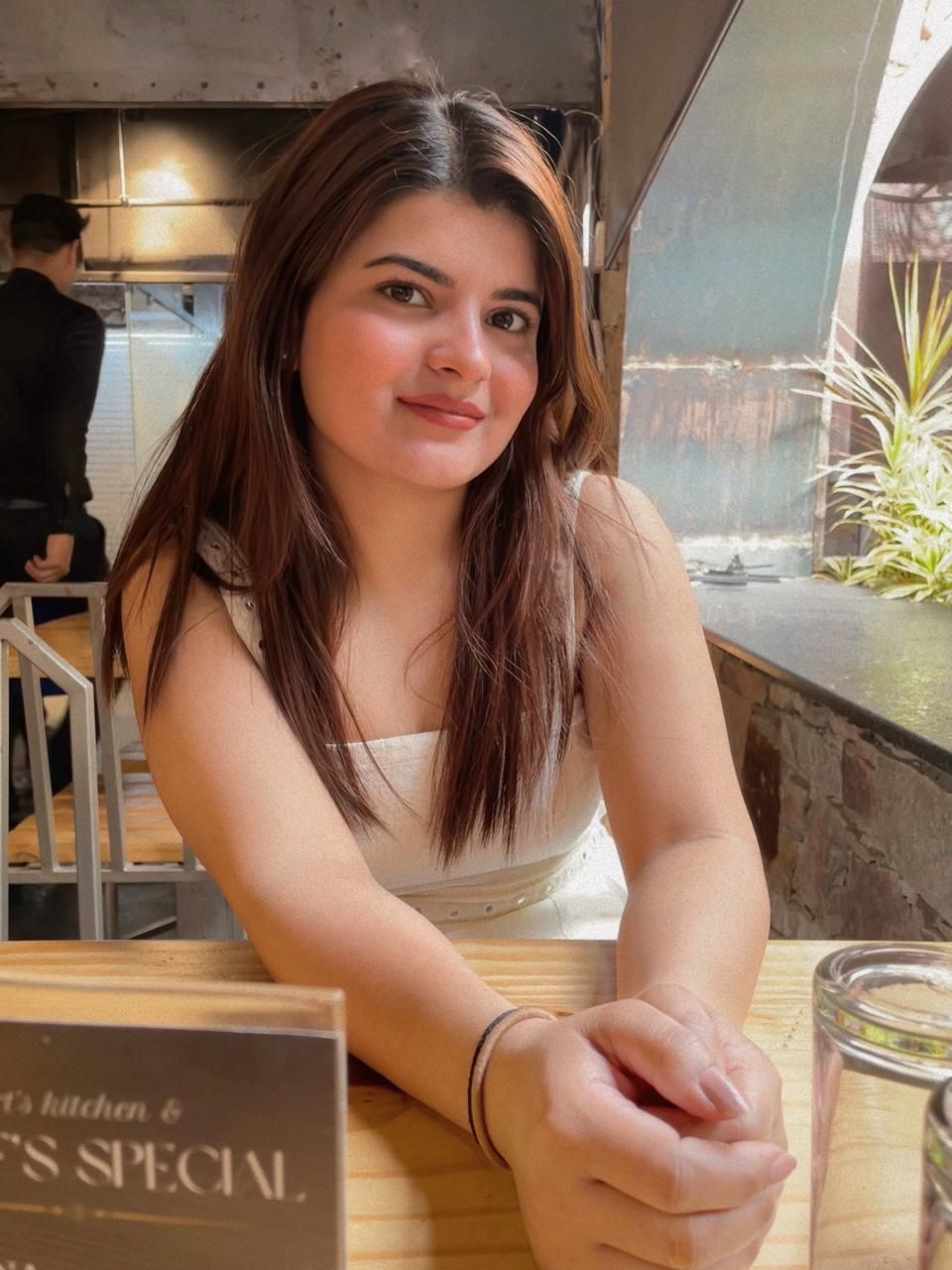 A man is sitting at a table holding a cup of coffee and using a laptop computer.