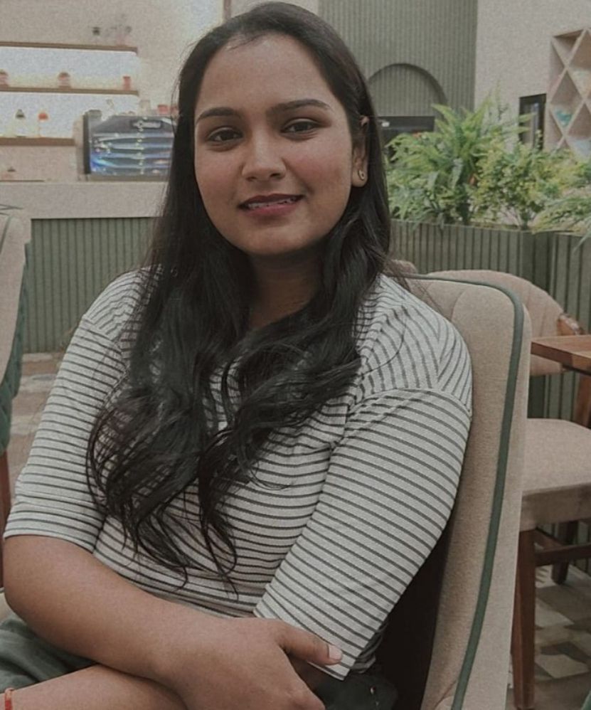 A man is sitting at a table holding a cup of coffee and using a laptop computer.