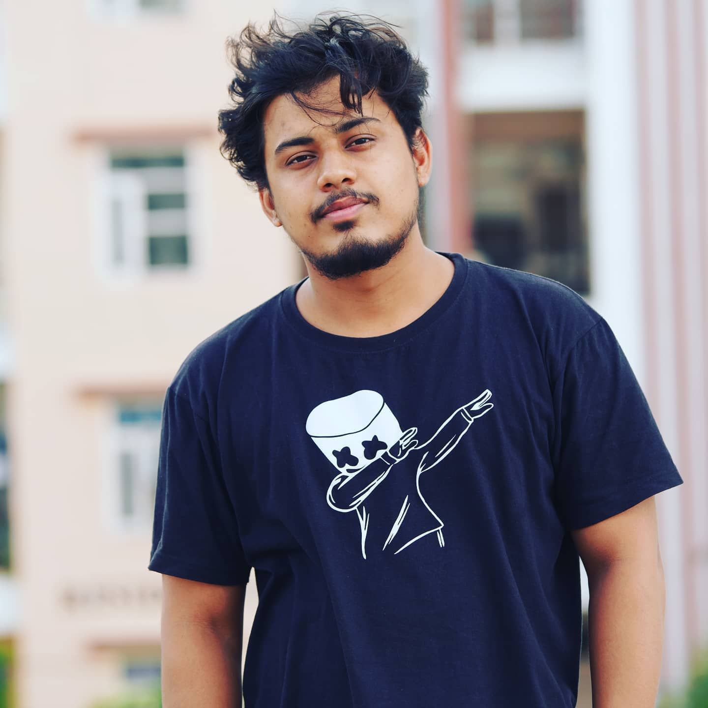 A man is sitting at a table holding a cup of coffee and using a laptop computer.