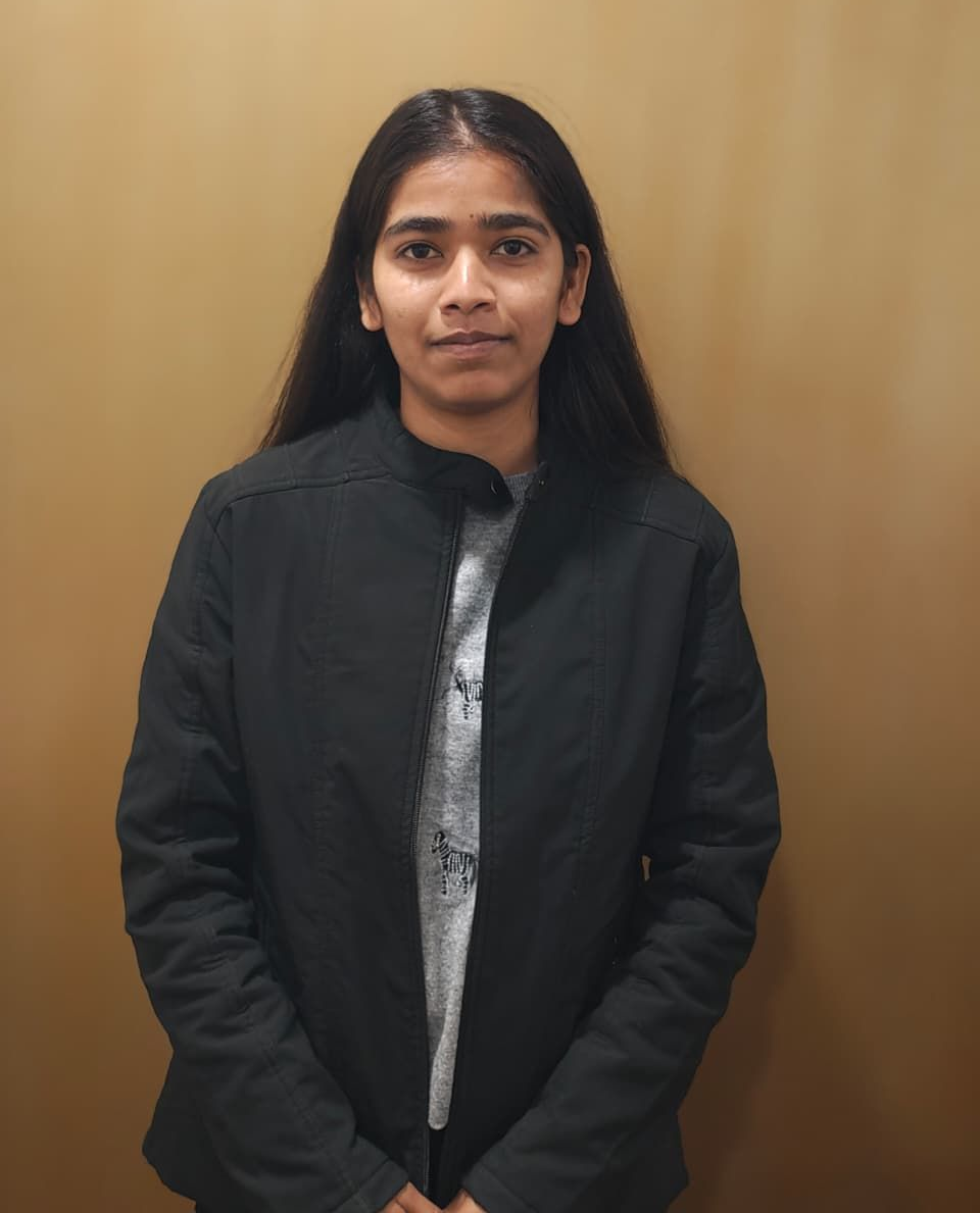 A man is sitting at a table holding a cup of coffee and using a laptop computer.