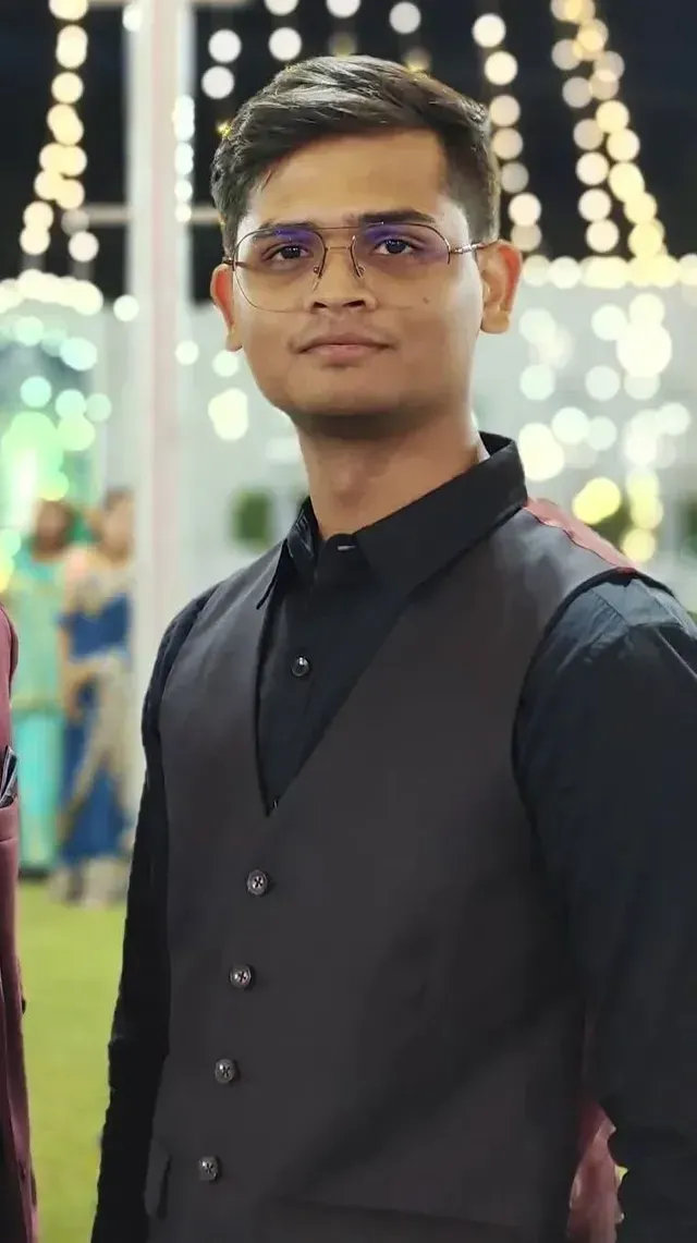 A man is sitting at a table holding a cup of coffee and using a laptop computer.