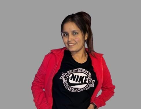 A man is sitting at a table holding a cup of coffee and using a laptop computer.