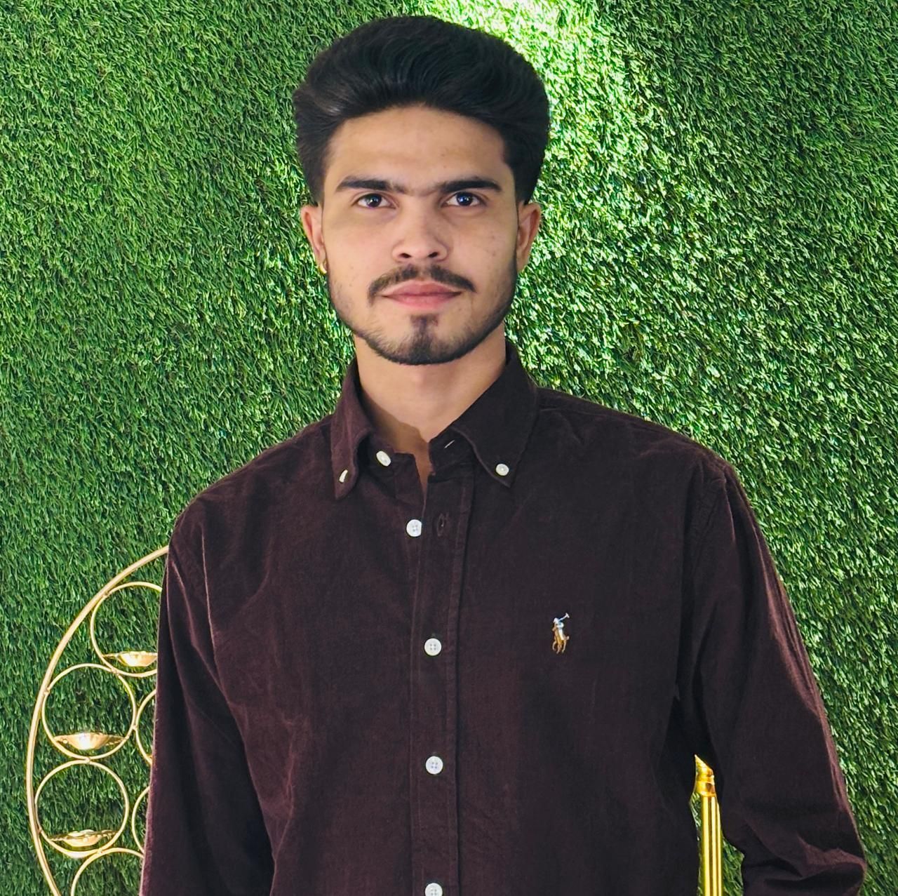 A man is sitting at a table holding a cup of coffee and using a laptop computer.