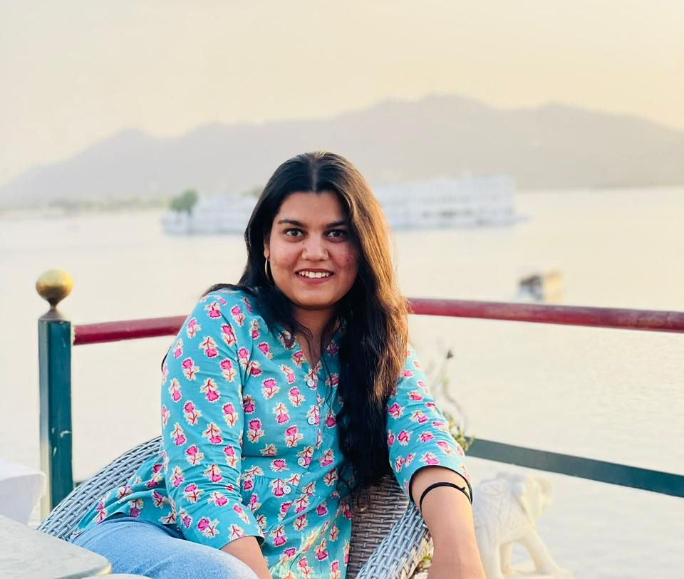 A man is sitting at a table holding a cup of coffee and using a laptop computer.