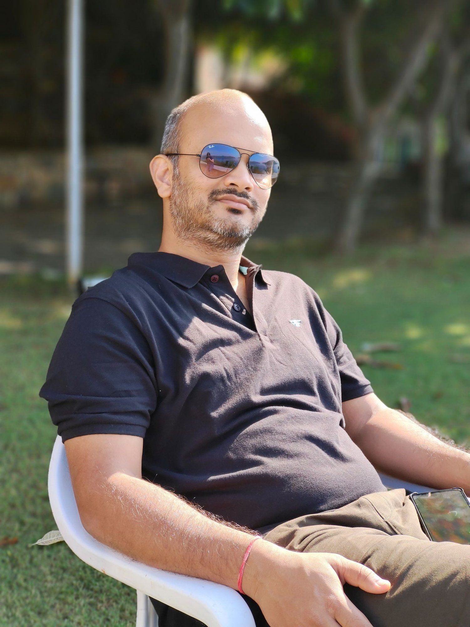 A man is sitting at a table holding a cup of coffee and using a laptop computer.