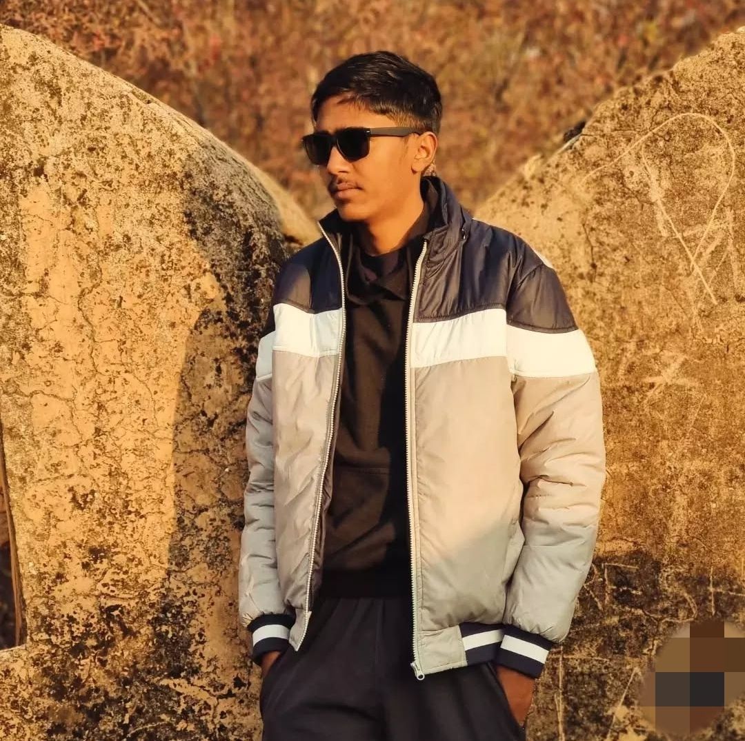 A man is sitting at a table holding a cup of coffee and using a laptop computer.