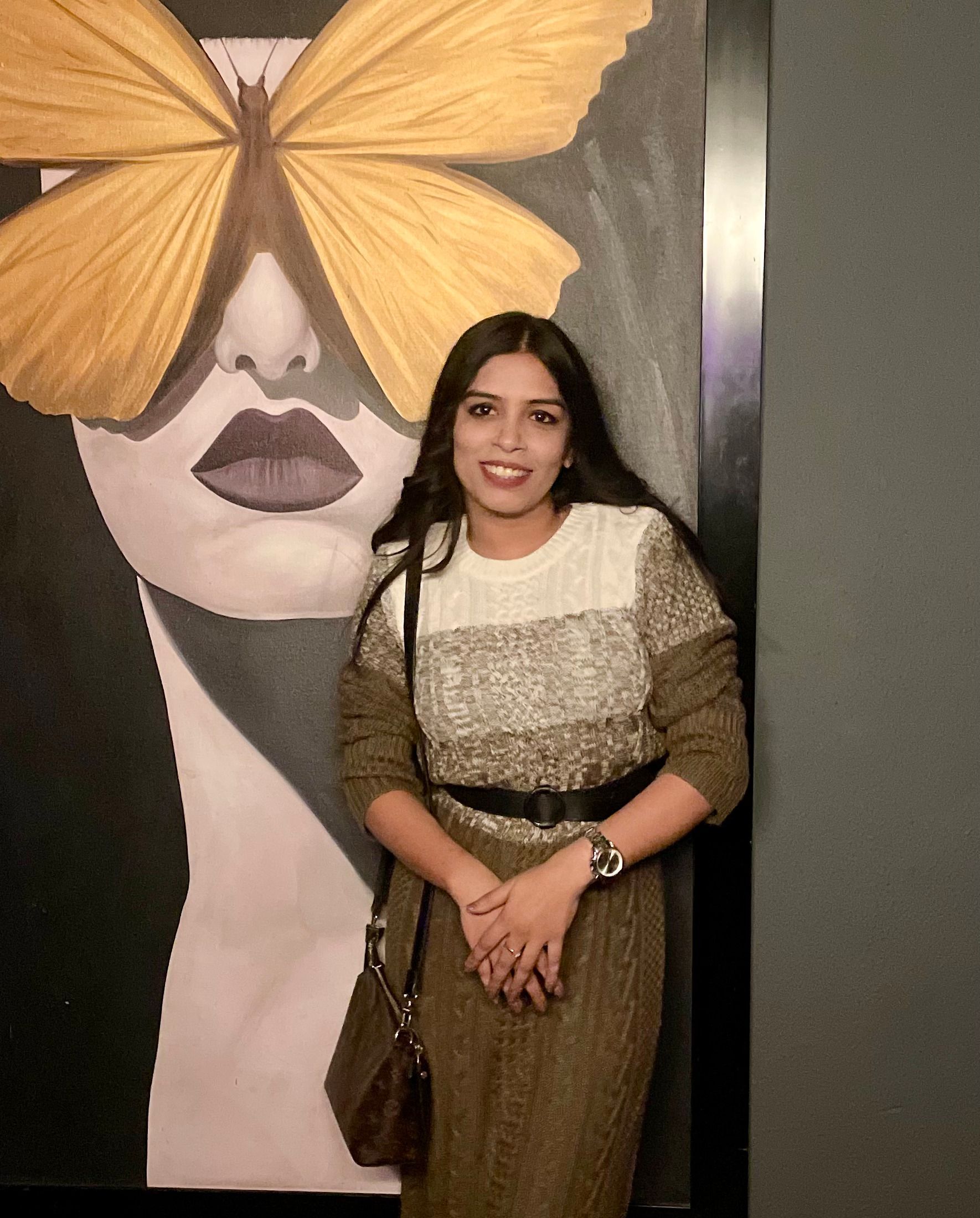 A man is sitting at a table holding a cup of coffee and using a laptop computer.