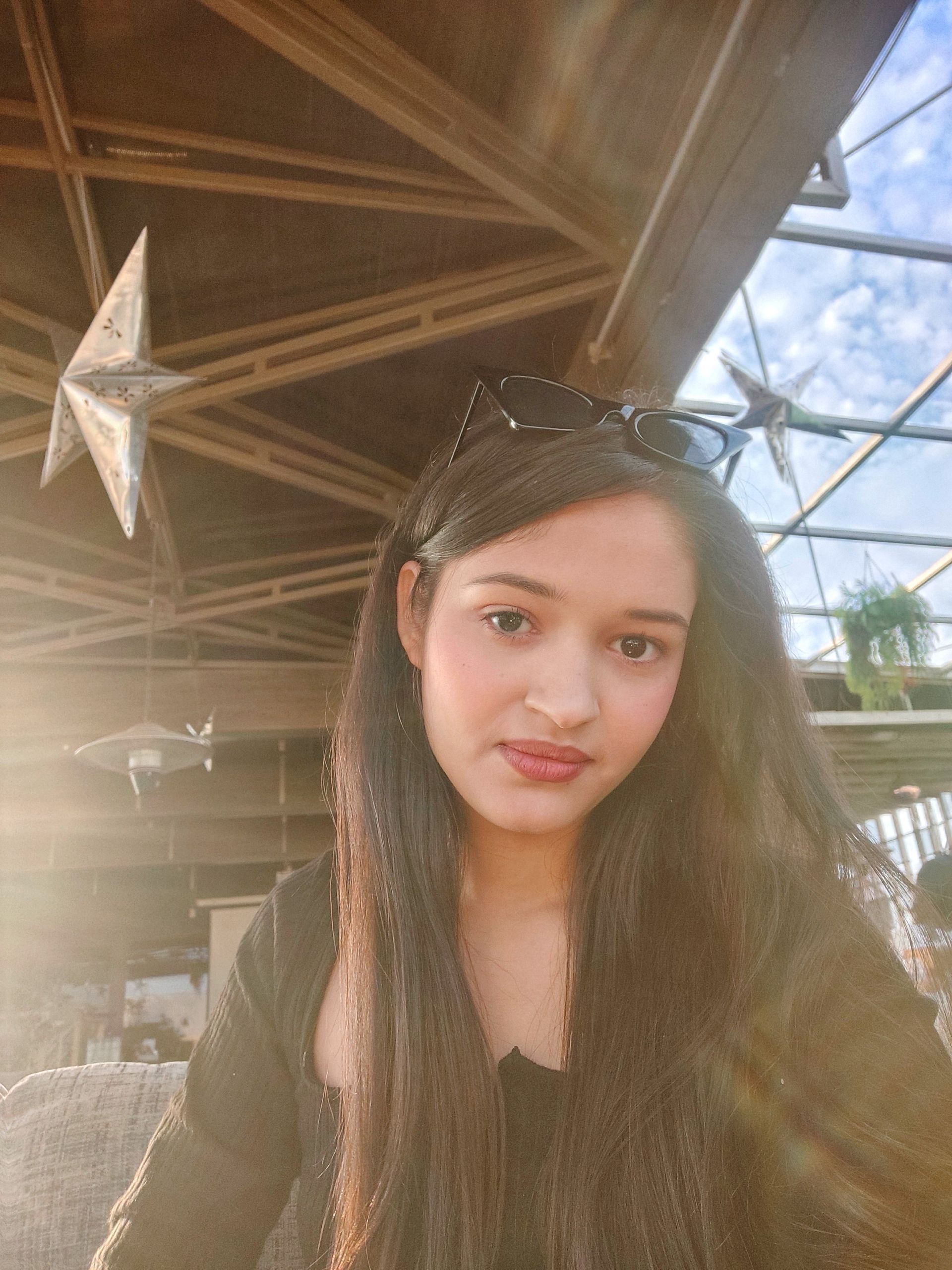 A man is sitting at a table holding a cup of coffee and using a laptop computer.
