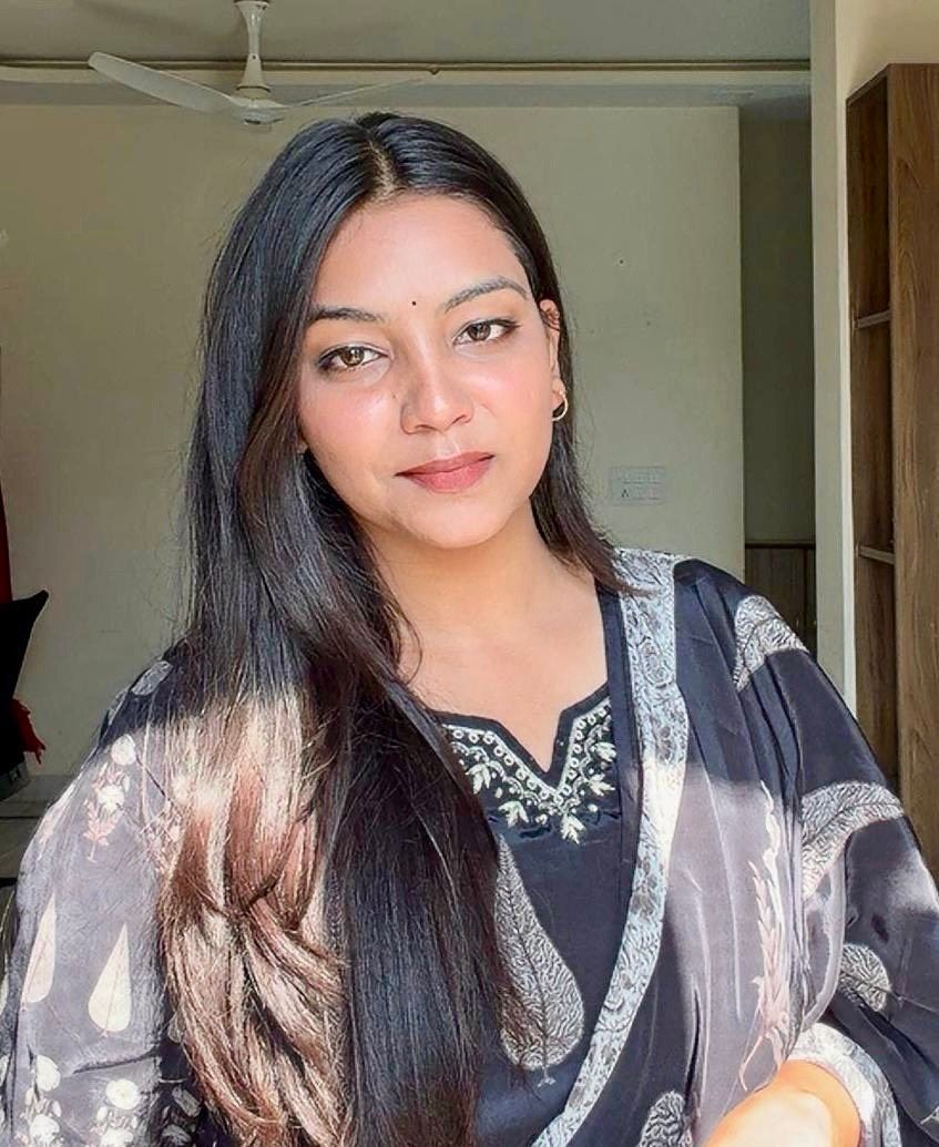 A man is sitting at a table holding a cup of coffee and using a laptop computer.