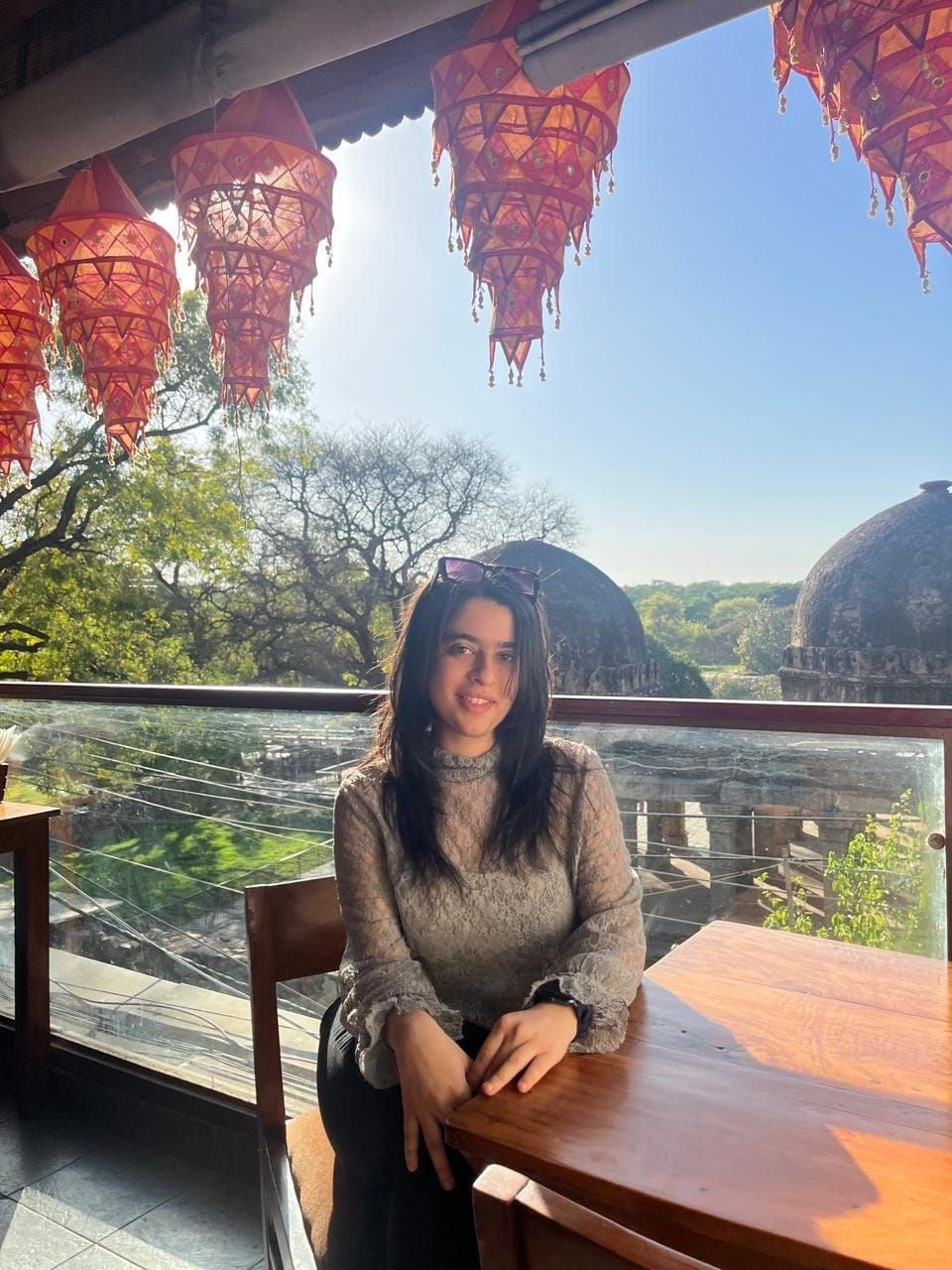A man is sitting at a table holding a cup of coffee and using a laptop computer.