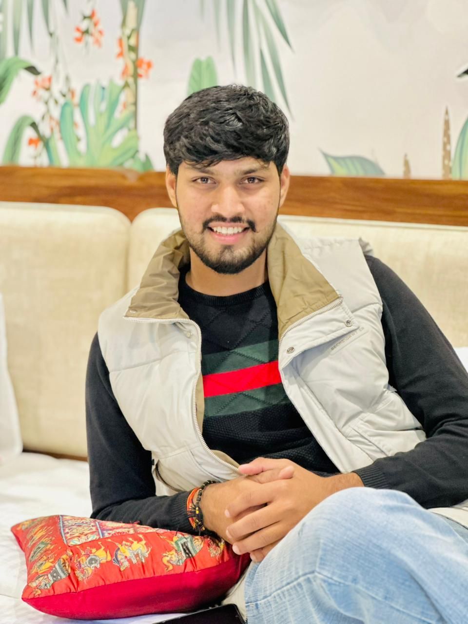 A man is sitting at a table holding a cup of coffee and using a laptop computer.