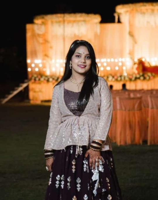 A man is sitting at a table holding a cup of coffee and using a laptop computer.
