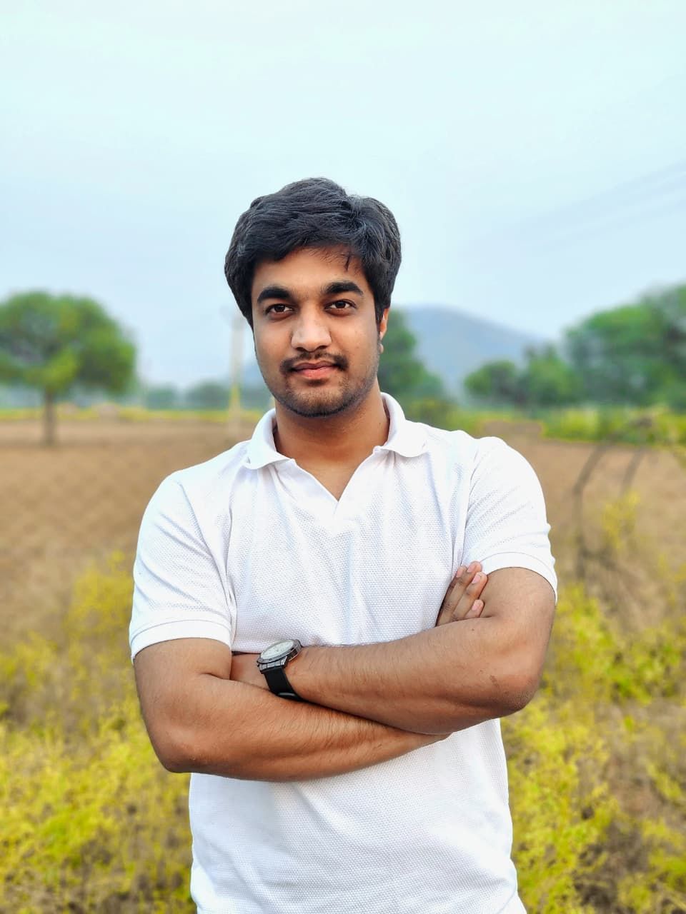 A man is sitting at a table holding a cup of coffee and using a laptop computer.